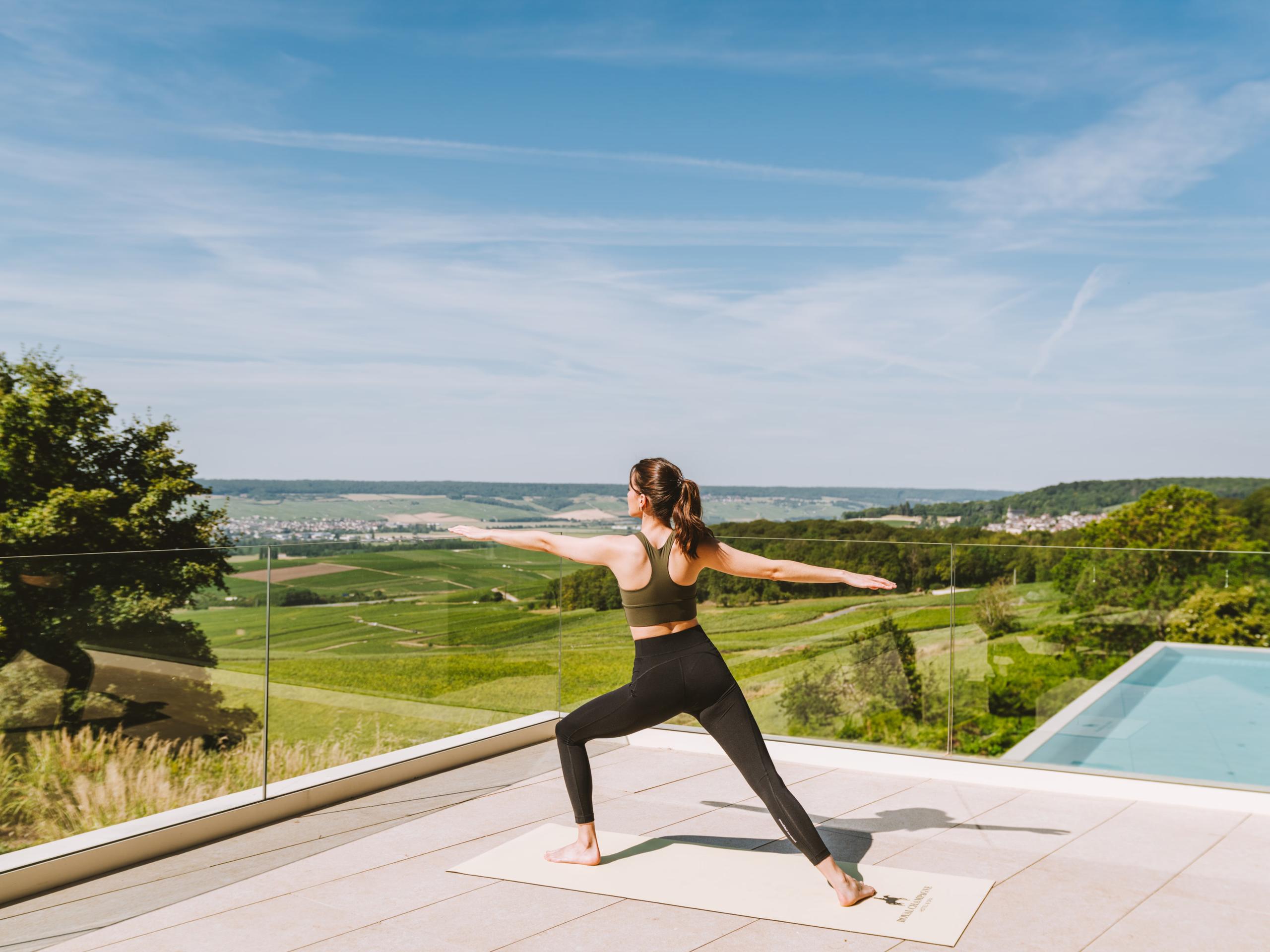 Royal Champagne Hotel & Spa: woman in yoga pose on terrace overlooking rolling vineyards and distant valleys