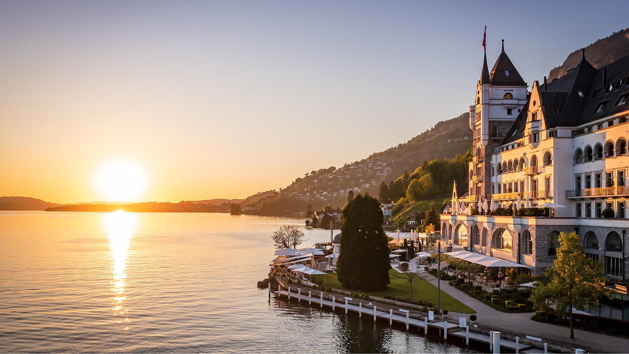 The castle-like hotel with twin spires at dusk on Lake Lucerne