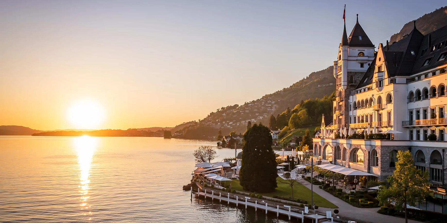 The castle-like hotel with twin spires at dusk on Lake Lucerne