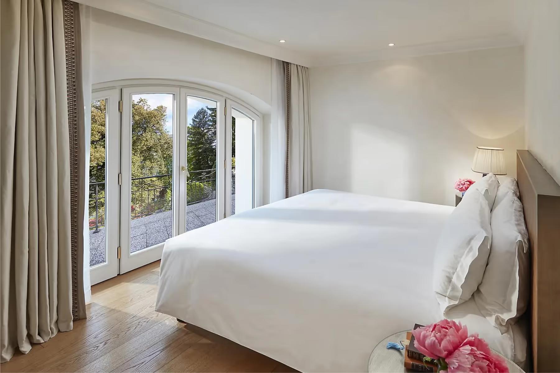 Mandarin Oriental, Lake Como: bedroom with white duvet, wood details, and wide windows framing mountain vista
