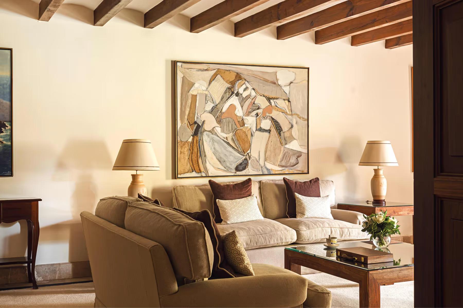 La Residencia: seating area with armchairs, beamed ceiling, framed artwork, and warm natural light