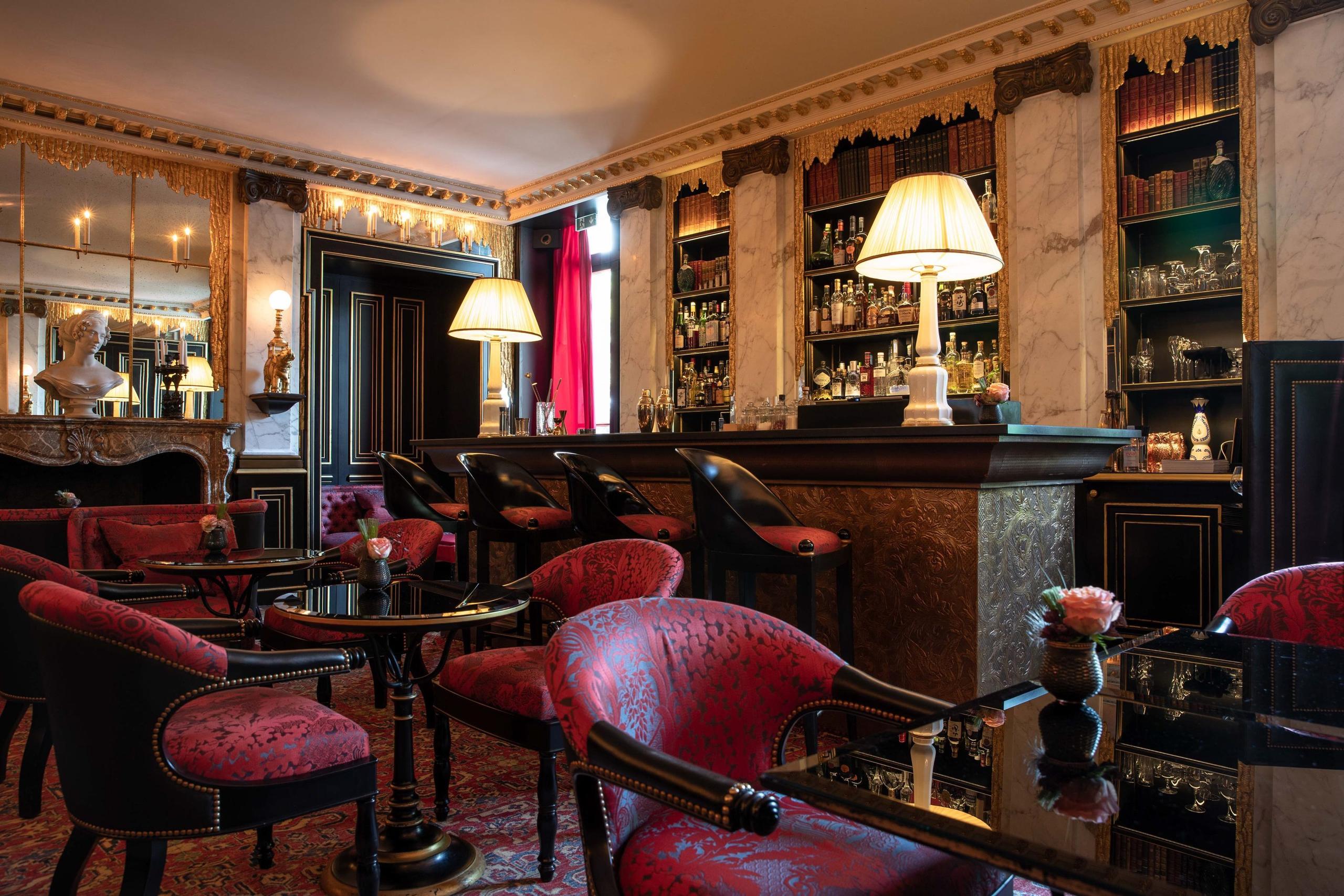 La Réserve Paris: an intimate lounge with burgundy velvet seating and warm oak cabinetry