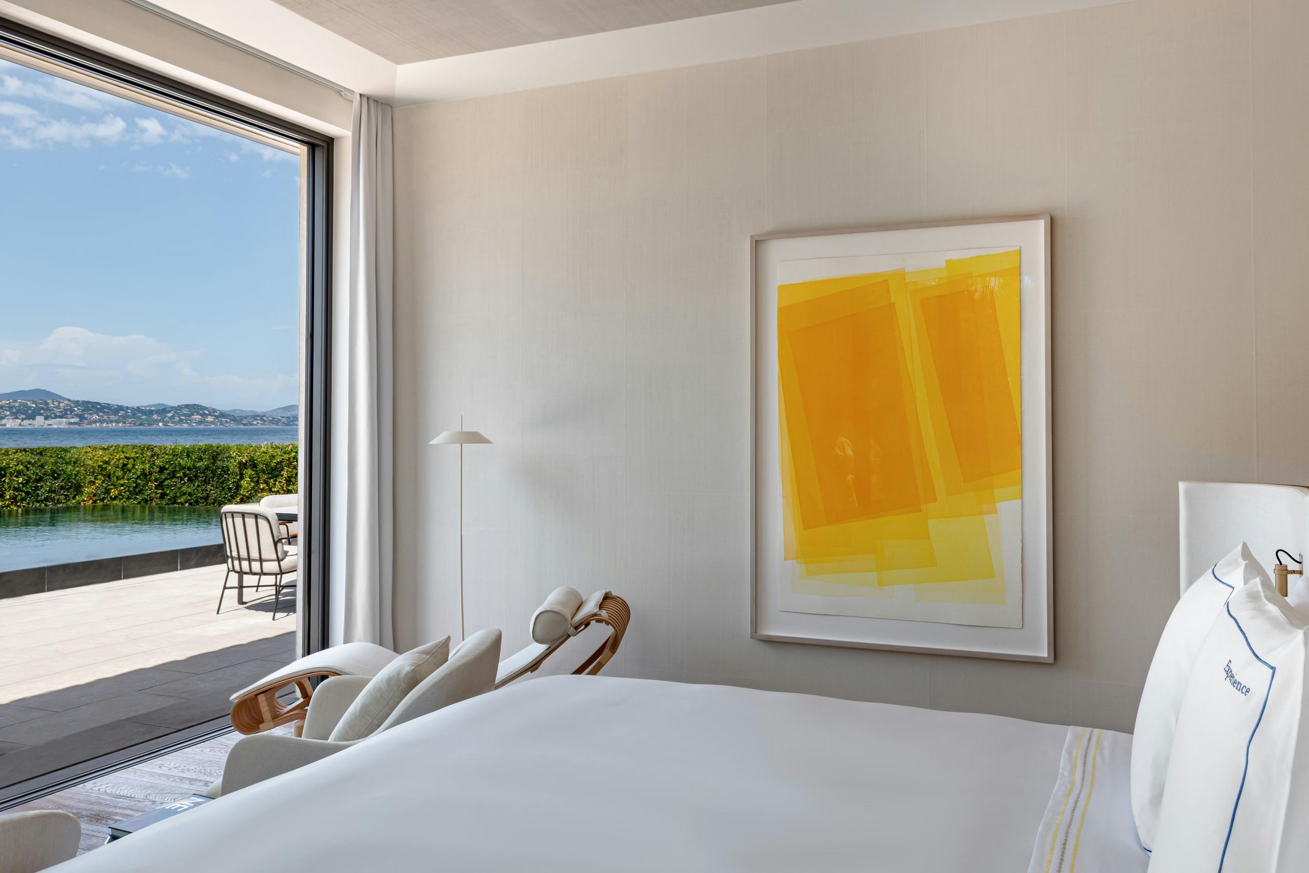 Bedroom corner with white bed and abstract yellow artwork