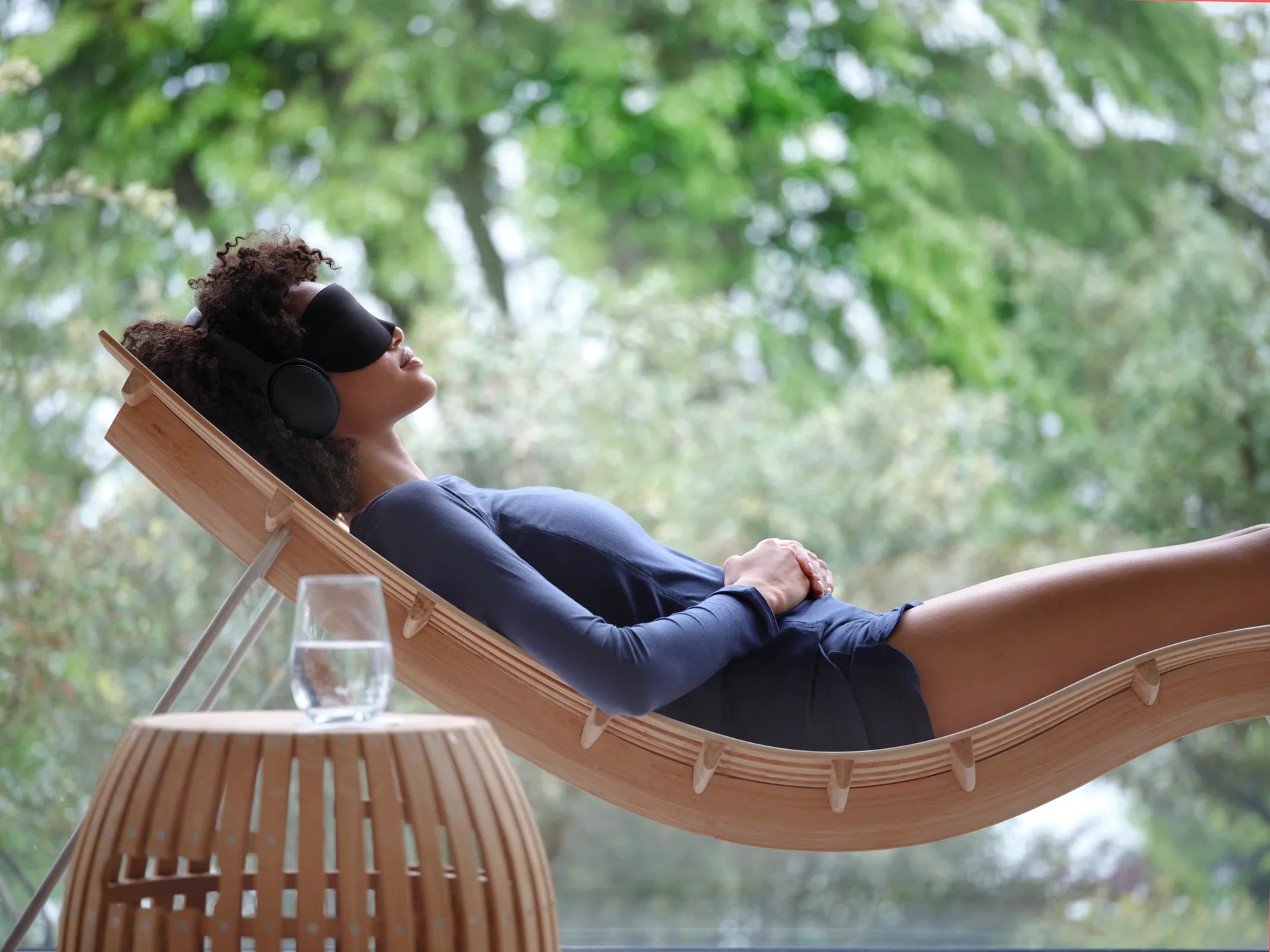 Chenot Palace Weggis: woman in black loungewear relaxing in wooden hammock suspended over green forest canopy