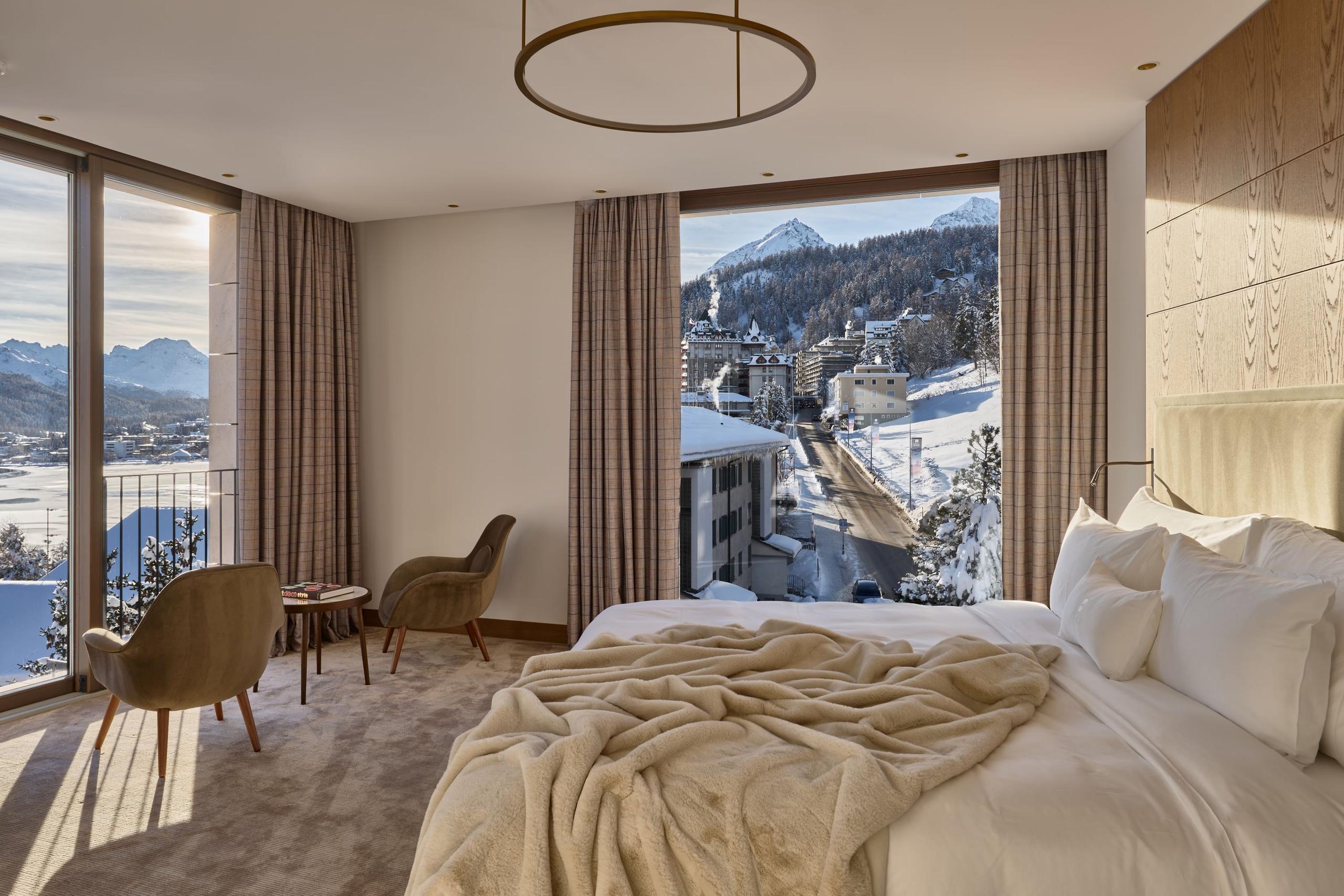 Grace La Margna St. Moritz: bedroom with cream bedding, wood furnishings, and floor-to-ceiling windows overlooking mountains