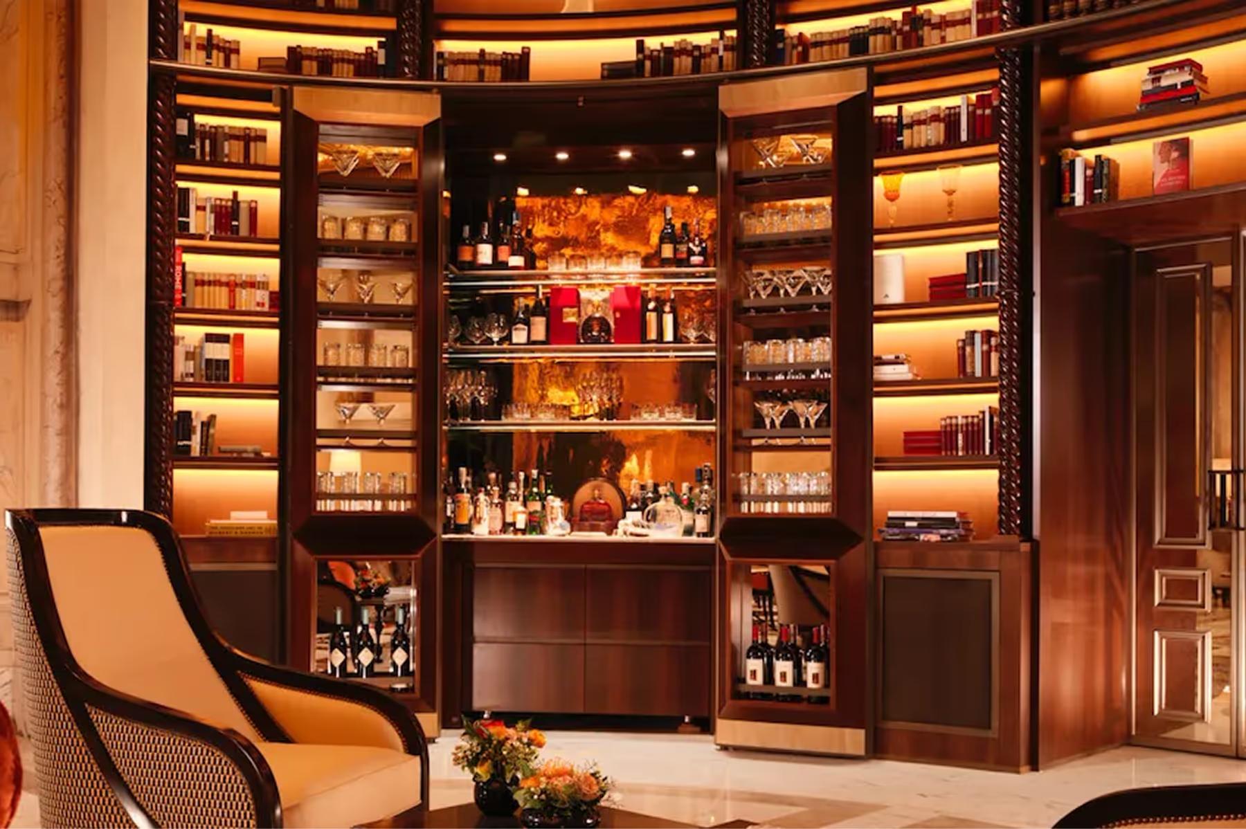 Hotel Eden: La Libreria lounge with wooden display cabinets, elegant furnishings, and warm lighting