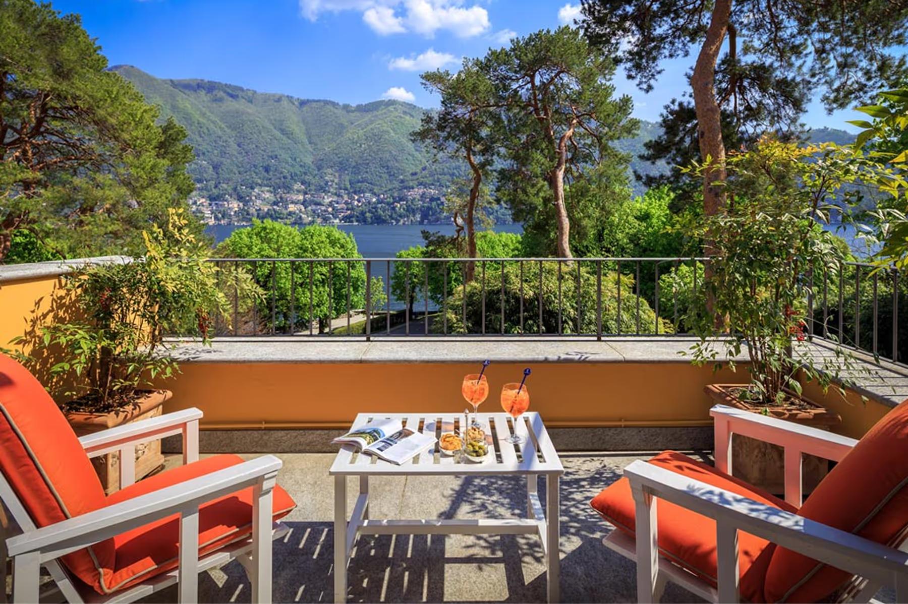 Waterfront terrace with coral cushioned chairs and panoramic lake and mountain views