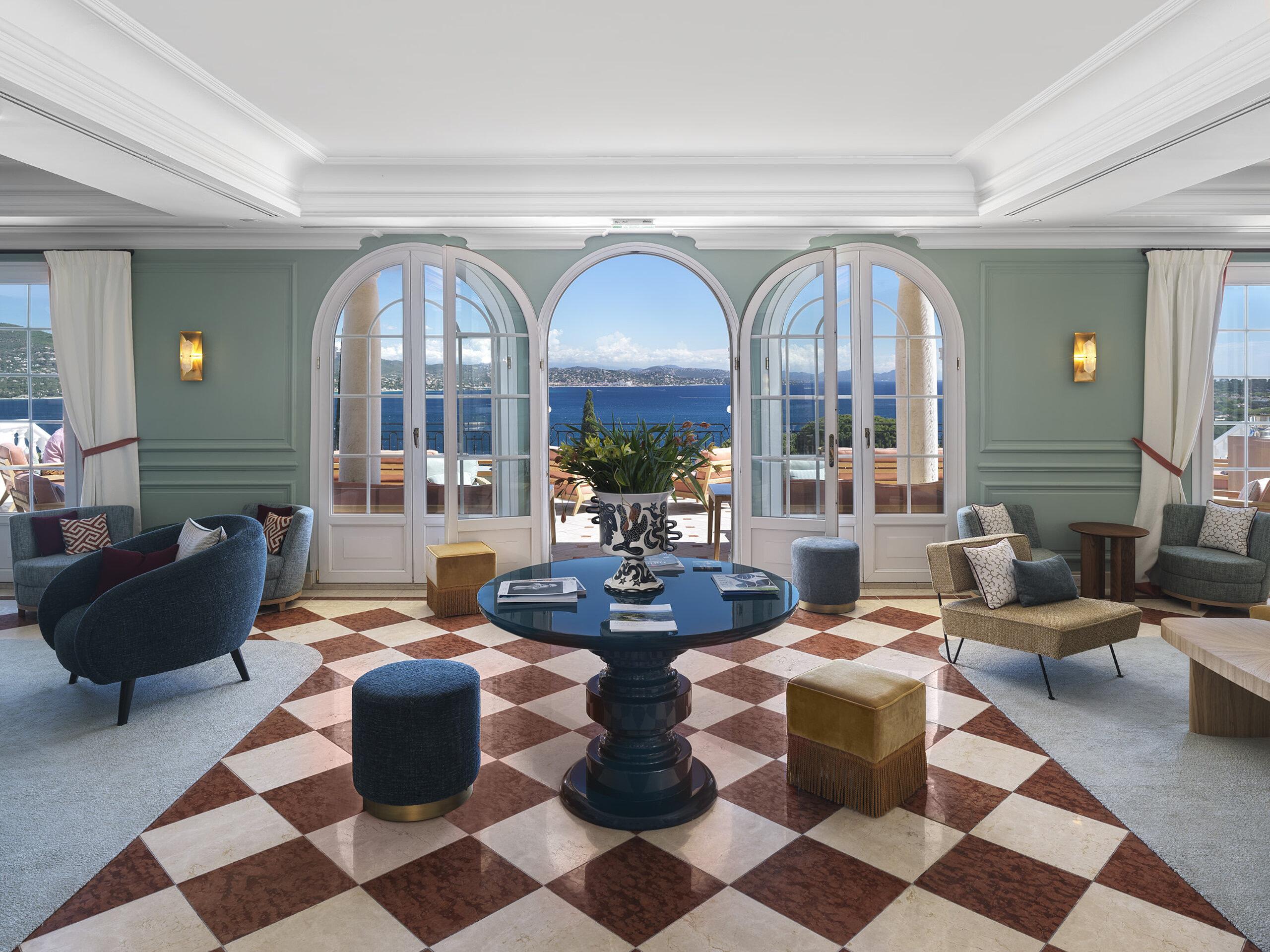 Althoff Villa Belrose: light-filled salon with arched glass doors framing a bay view, marble floor pattern in warm tones