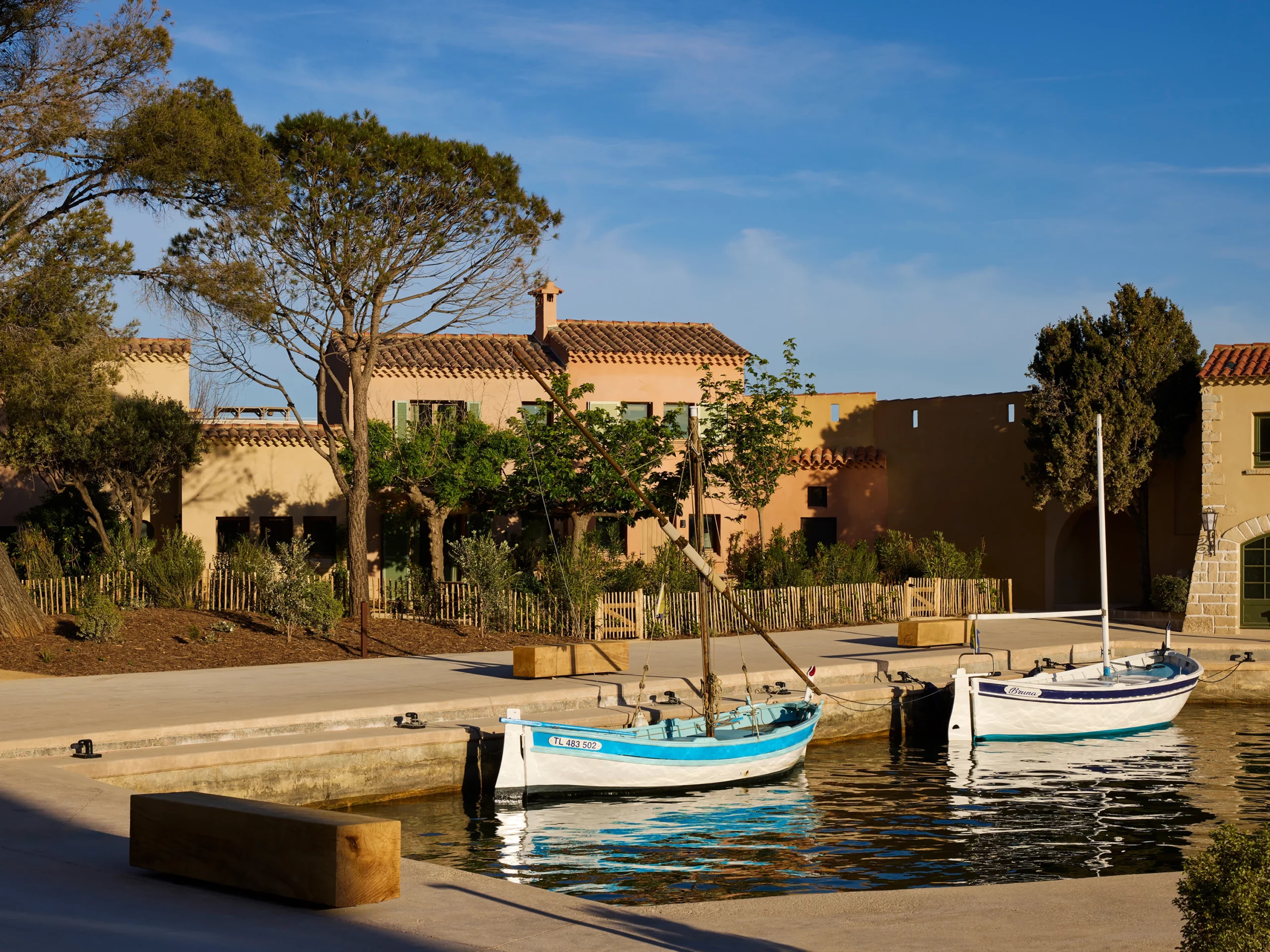 Traditional blue and white fishing boats moor at the quay before pastel harbor houses