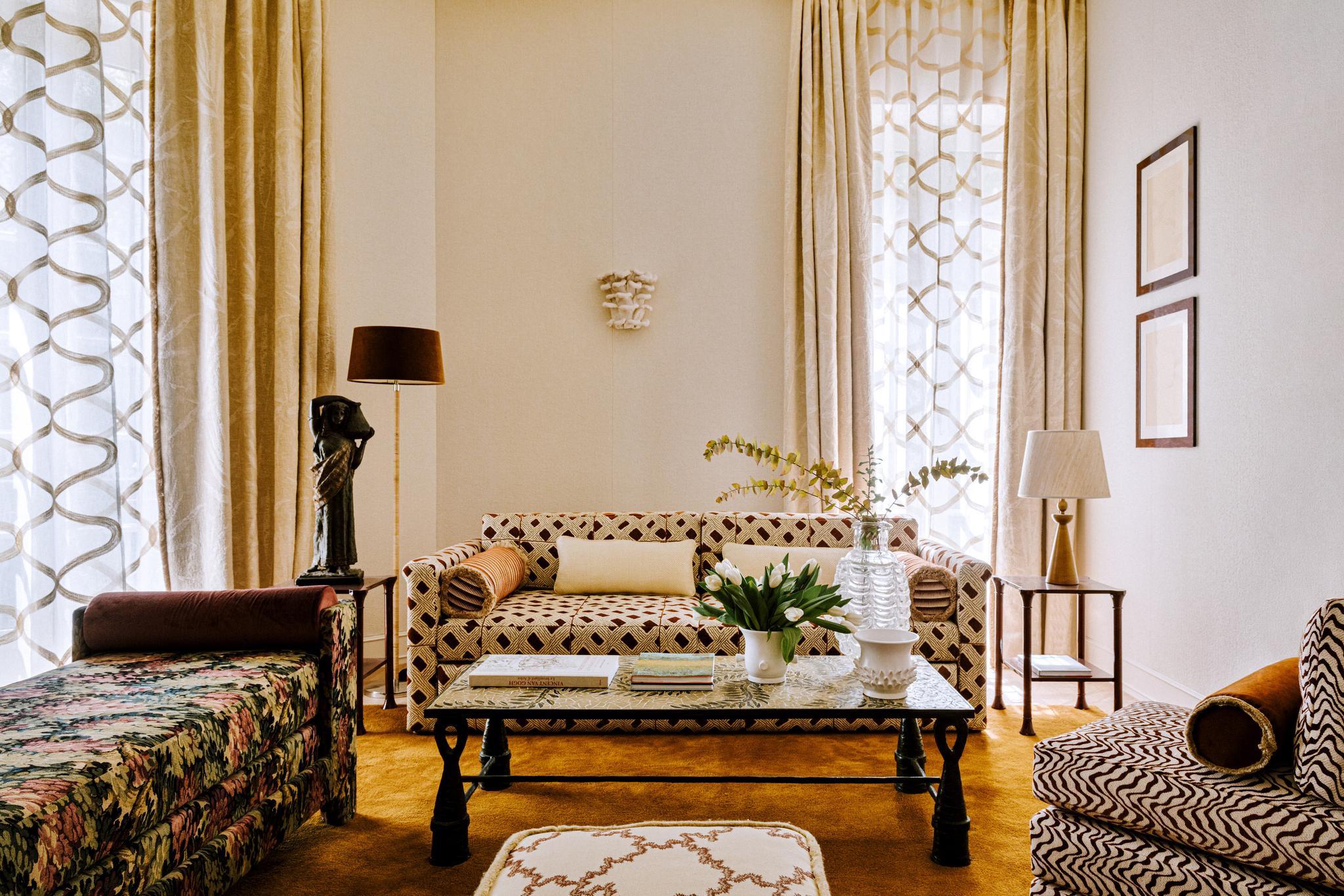 Suite sitting area with geometric patterned sofa, tall window with garden light, parquet flooring