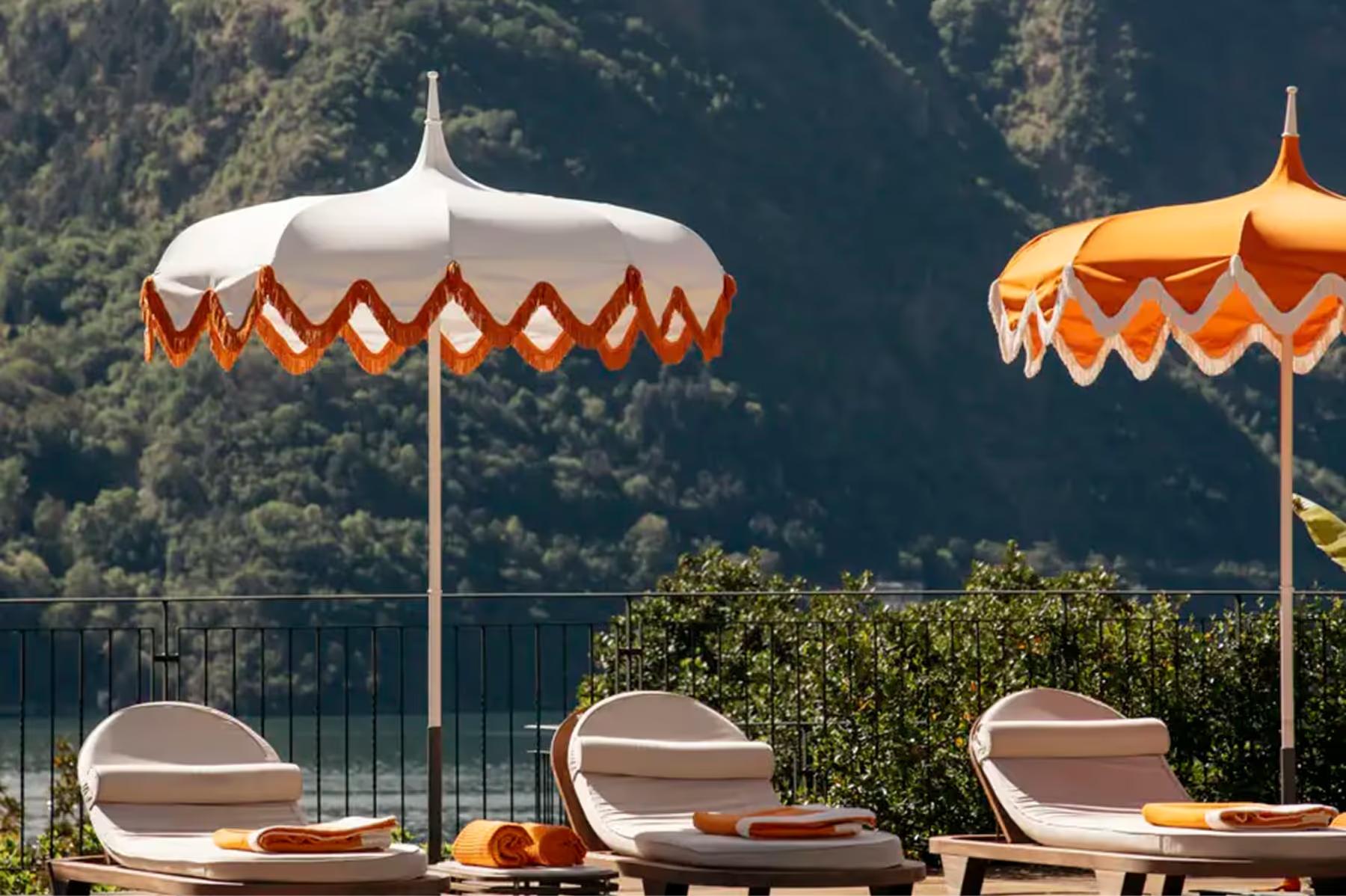 Loungers beneath striped umbrellas with lake and mountain views