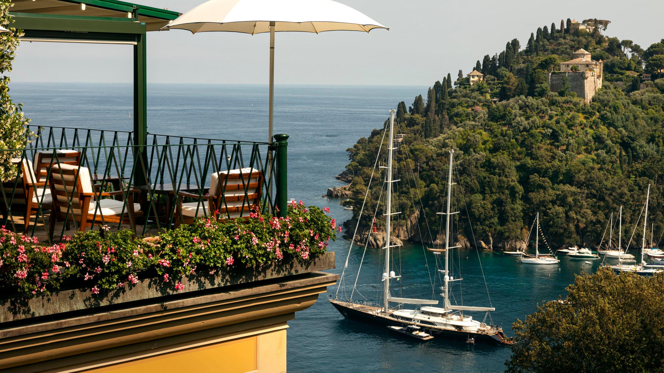 A terrace restaurant overlooking the harbor with sailboats and forested coastline