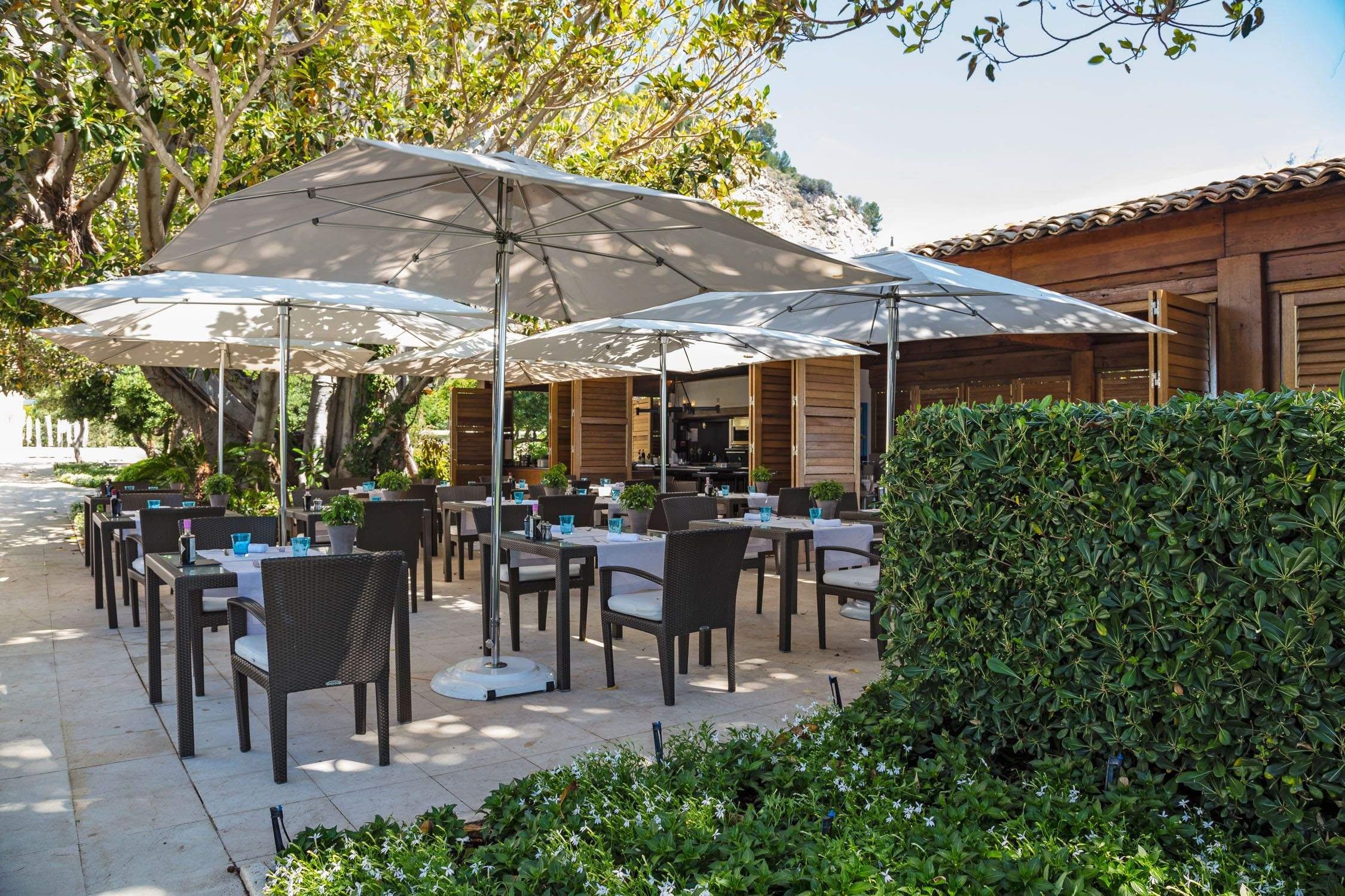 Black chairs under market umbrellas on a modern stone patio
