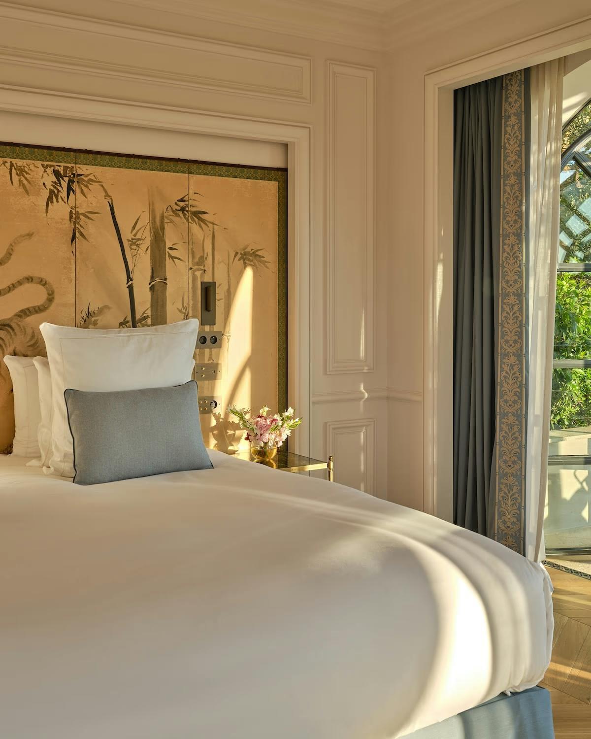 A bedroom at Château de la Messardière with a gilded bamboo screen above the bed