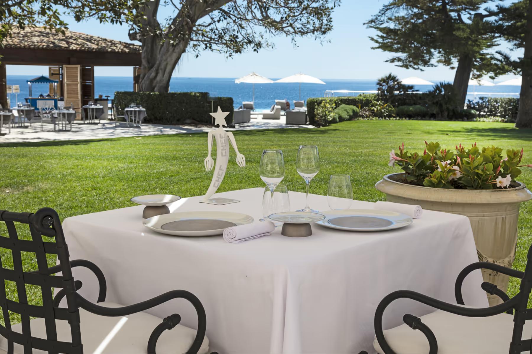 Hotel Cap-Estel: a round dining table under ancient trees with sea views beyond