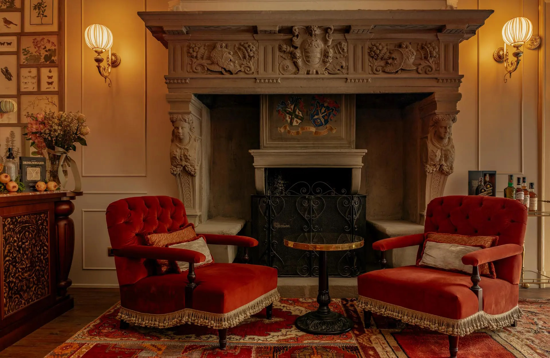 Passalacqua: a fireplace with ornate carved mantel, red seating, and framed artwork