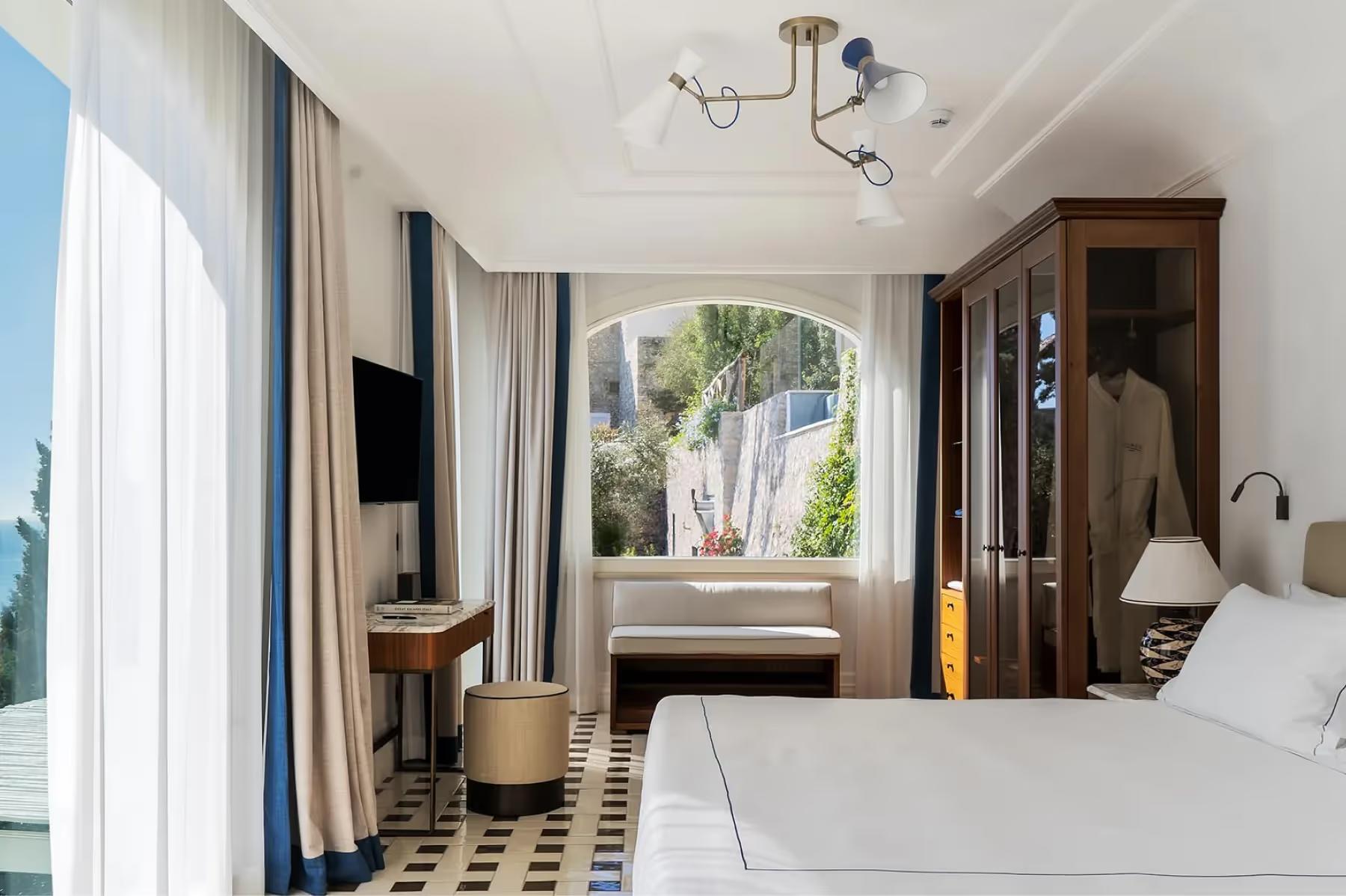 Contemporary bedroom featuring arched window, linen drapes, and Mediterranean views