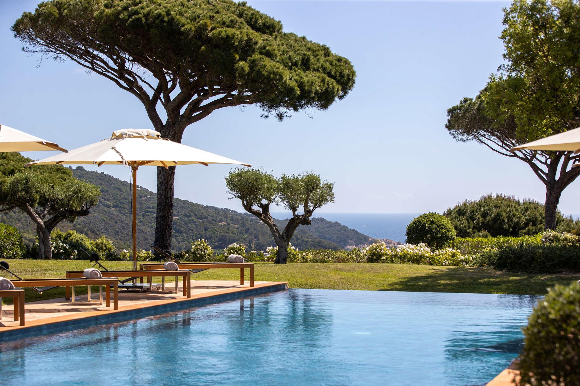 La Réserve Ramatuelle: pool surrounded by Mediterranean pines with lounge seating and umbrellas