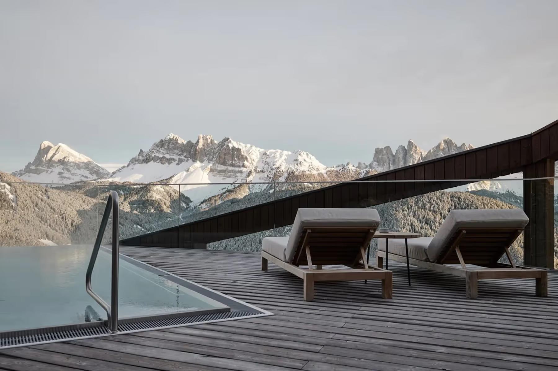 Forestis: a guest area with floor-to-ceiling windows, light wood furnishings, and expansive mountain vistas