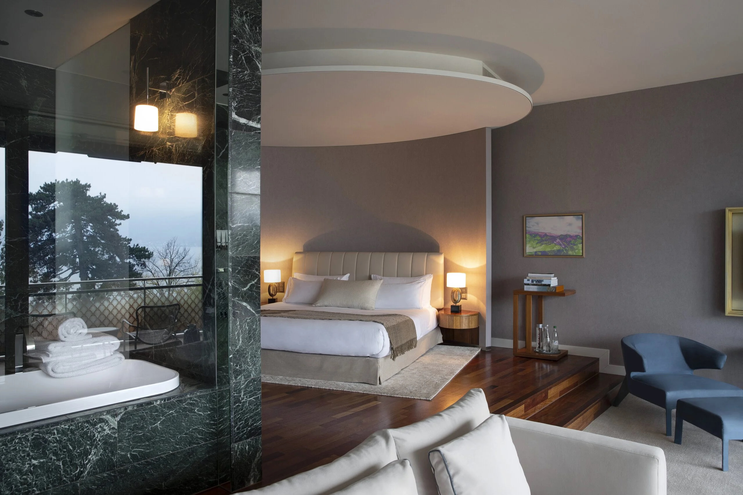 Chenot Palace Weggis: contemporary bedroom with curved ceiling detail, pendant lighting, and sitting area