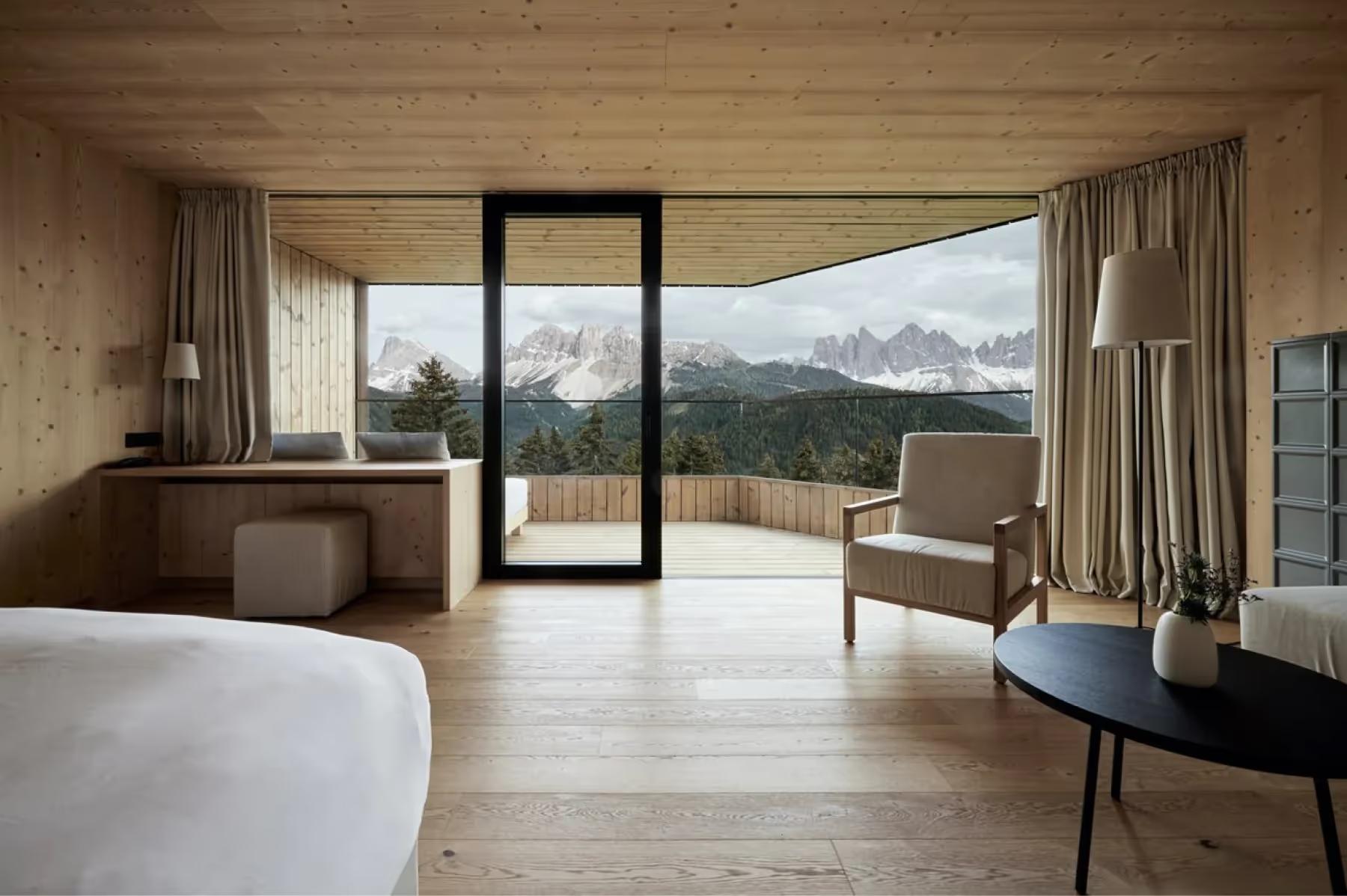 Forestis: a guest suite with expansive glass doors opening onto a terrace with mountain views in daylight