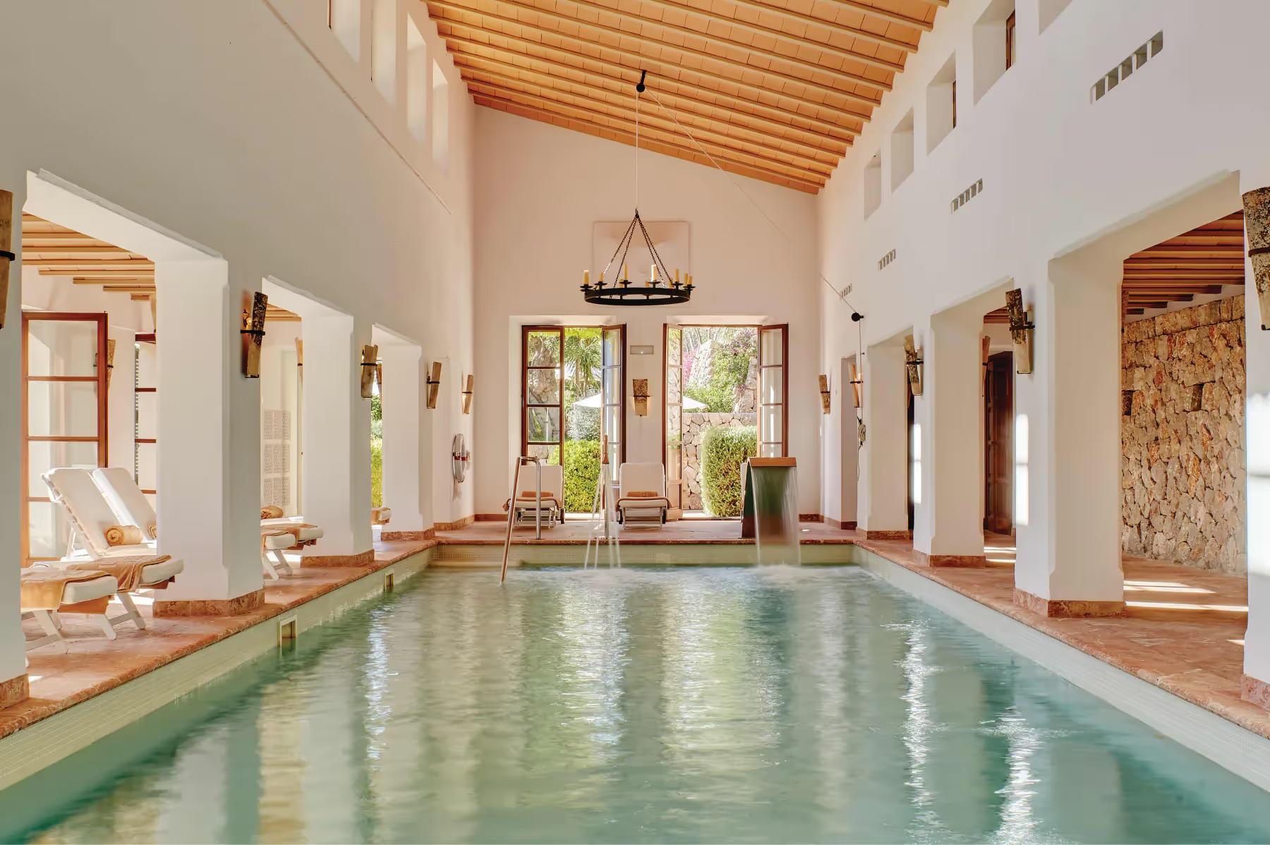 La Residencia: indoor swimming pool with wooden ceiling, cream stone columns, and natural light
