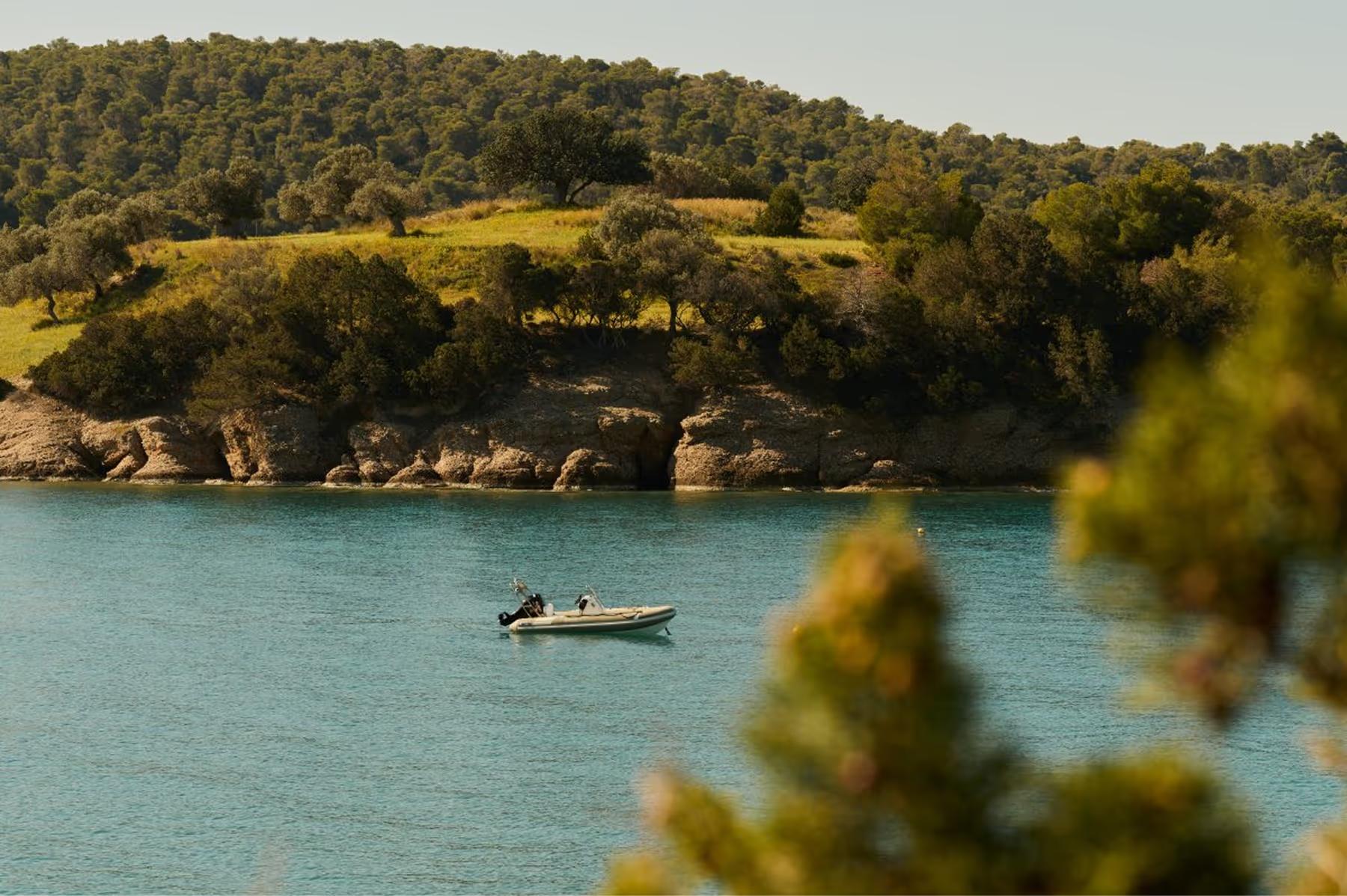 Amanzoe: boat moored in shallow turquoise waters near forested coast