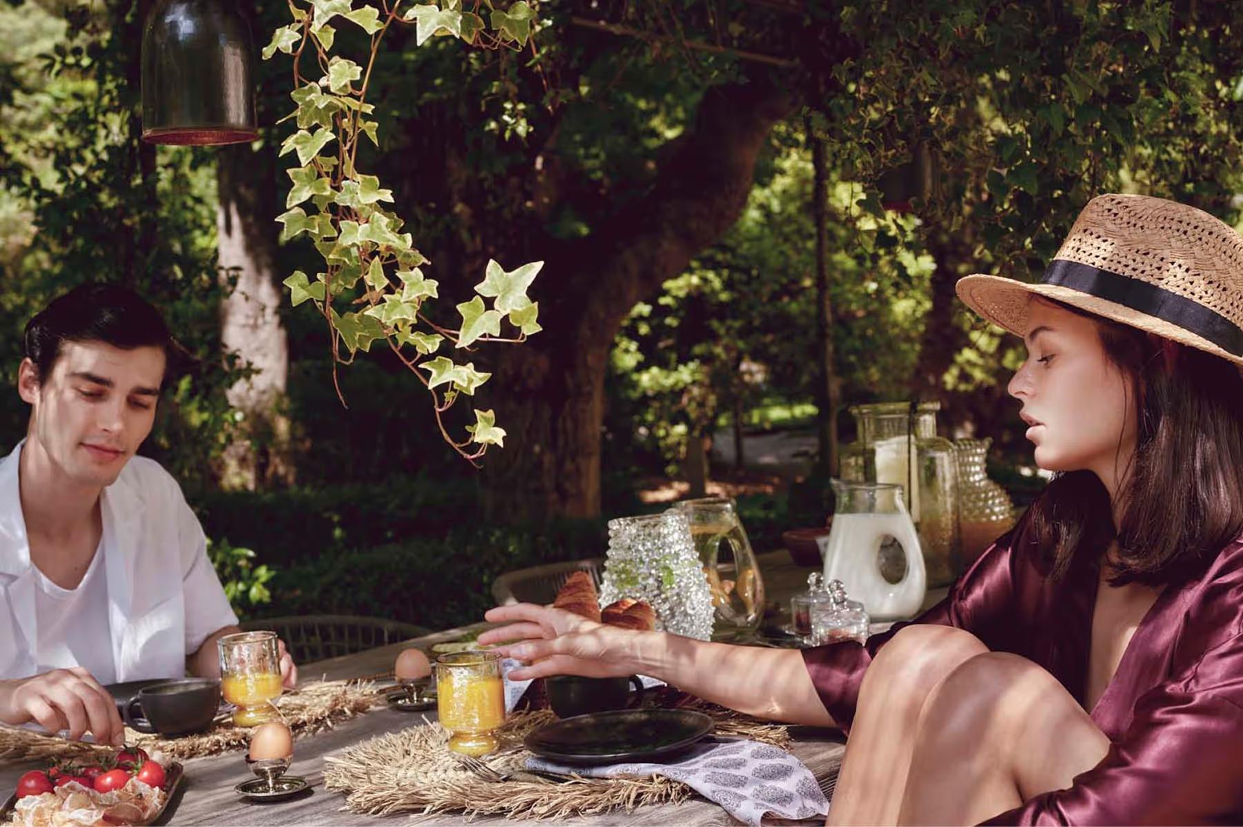 Le Mas de Chabran: two guests dining alfresco with candlelit table under dappled tree shade at dusk