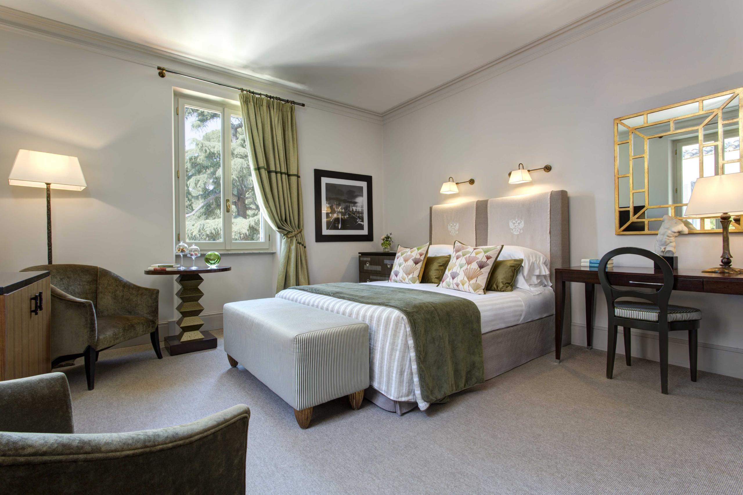 Bedroom with white bedding, green accents, and furnishings with garden windows