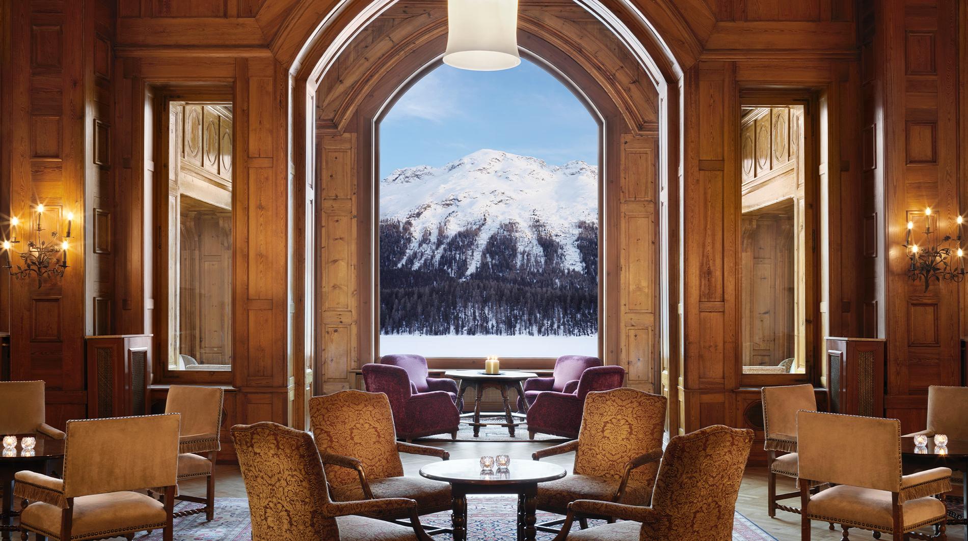 Badrutt’s Palace Hotel: wood-paneled lounge with arched doorway framing snow-capped mountain