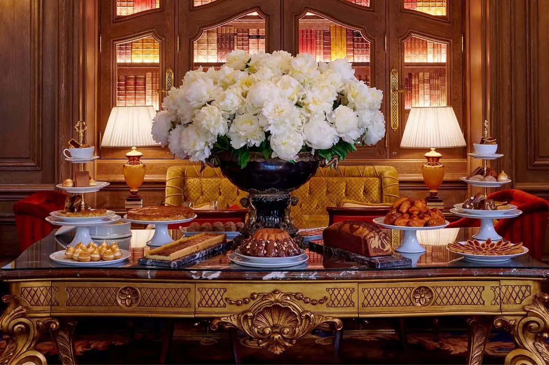 A console table with cream flowers, gilt accessories, and ornate wood paneling