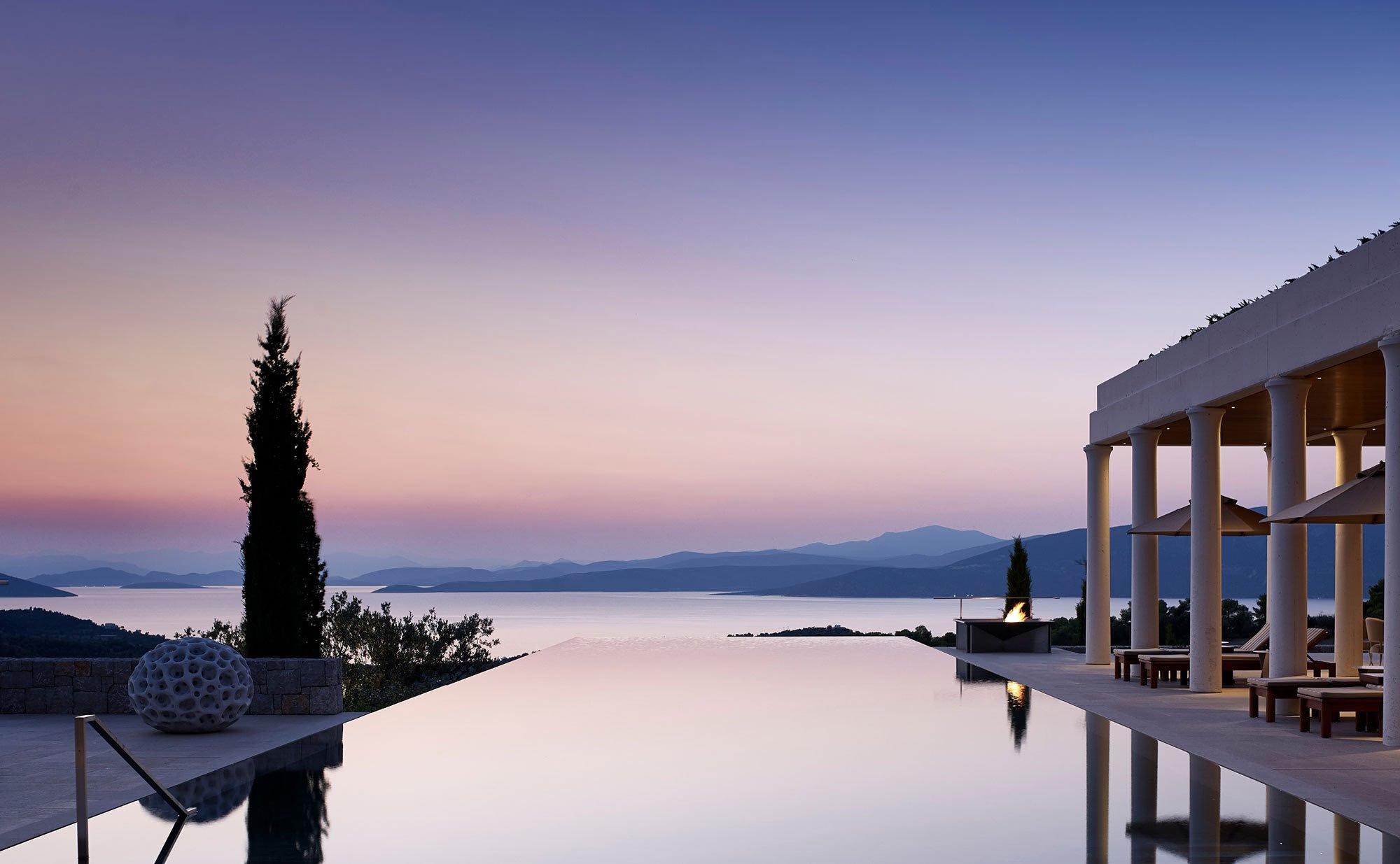 Amanzoe: hillside terrace at sunset with loungers and seascape backdrop