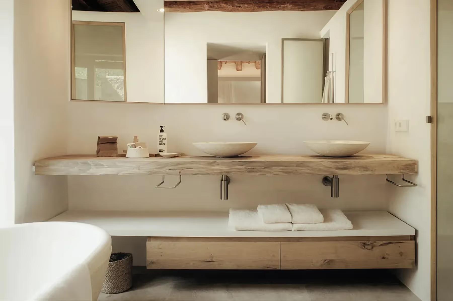 Minimalist bathroom with live-edge wood countertop, paired mirrors, and recessed lighting above sink