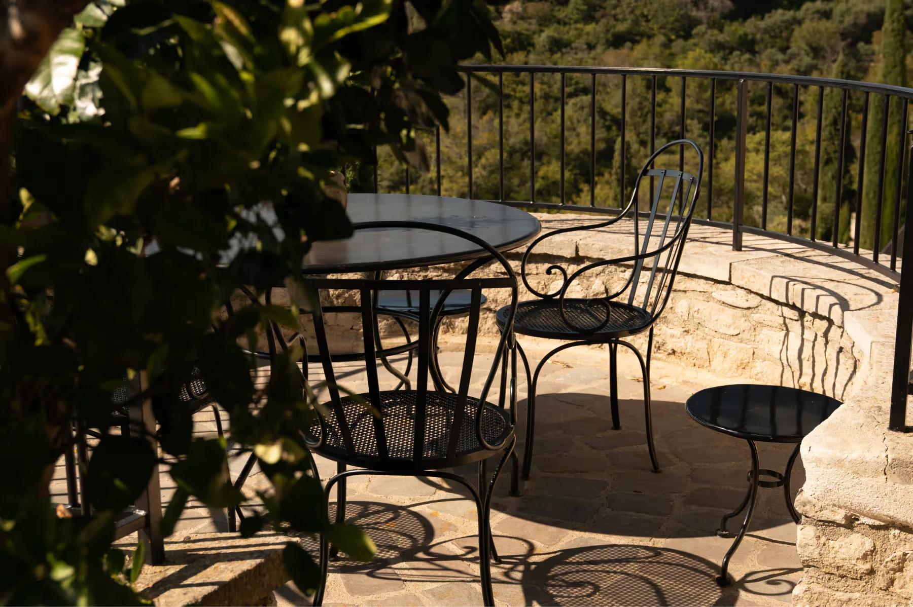 Outdoor seating on stone terrace framed by shadows and greenery