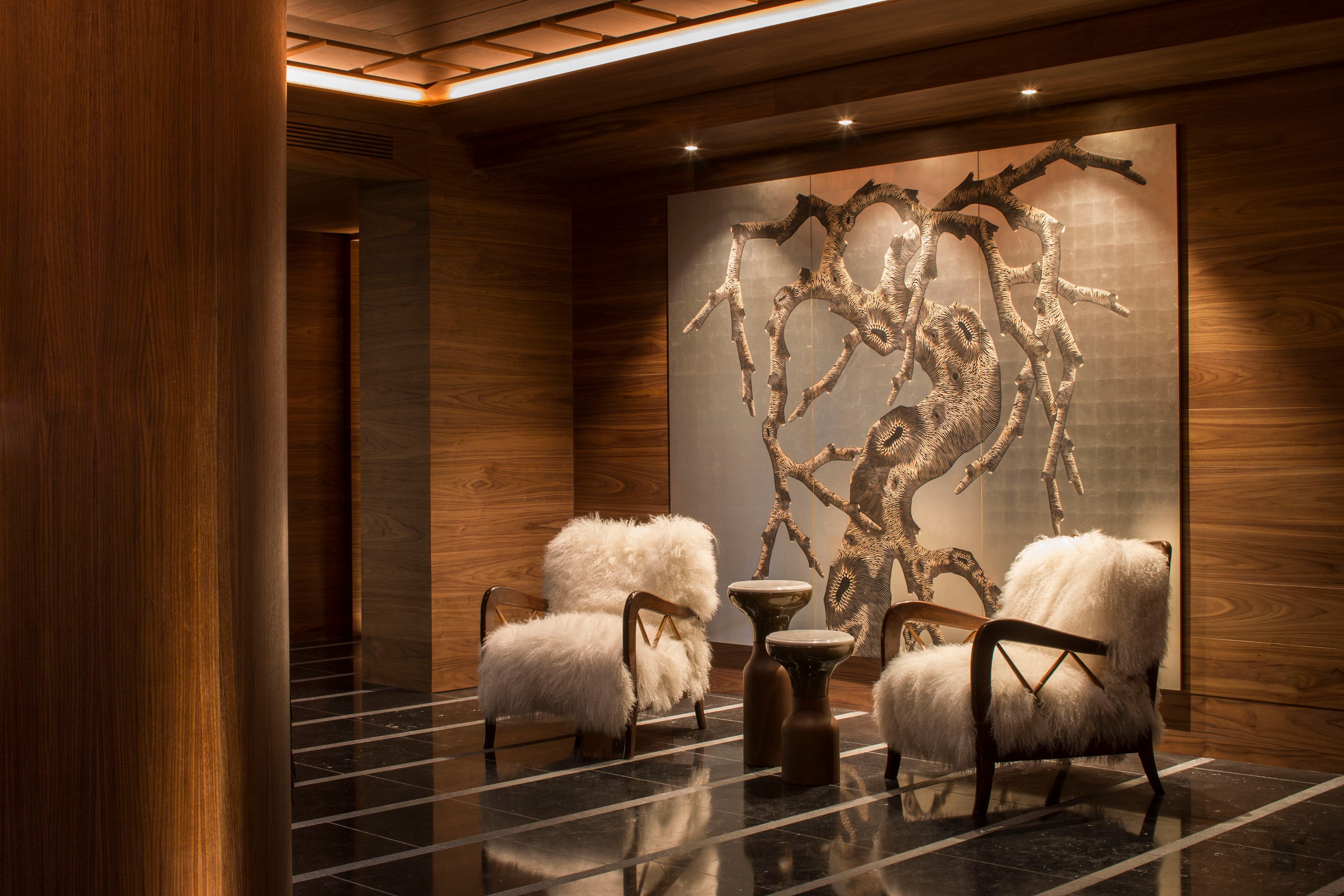 The spa lounge at Four Seasons Resort Megève with shearling chairs and a branch mural