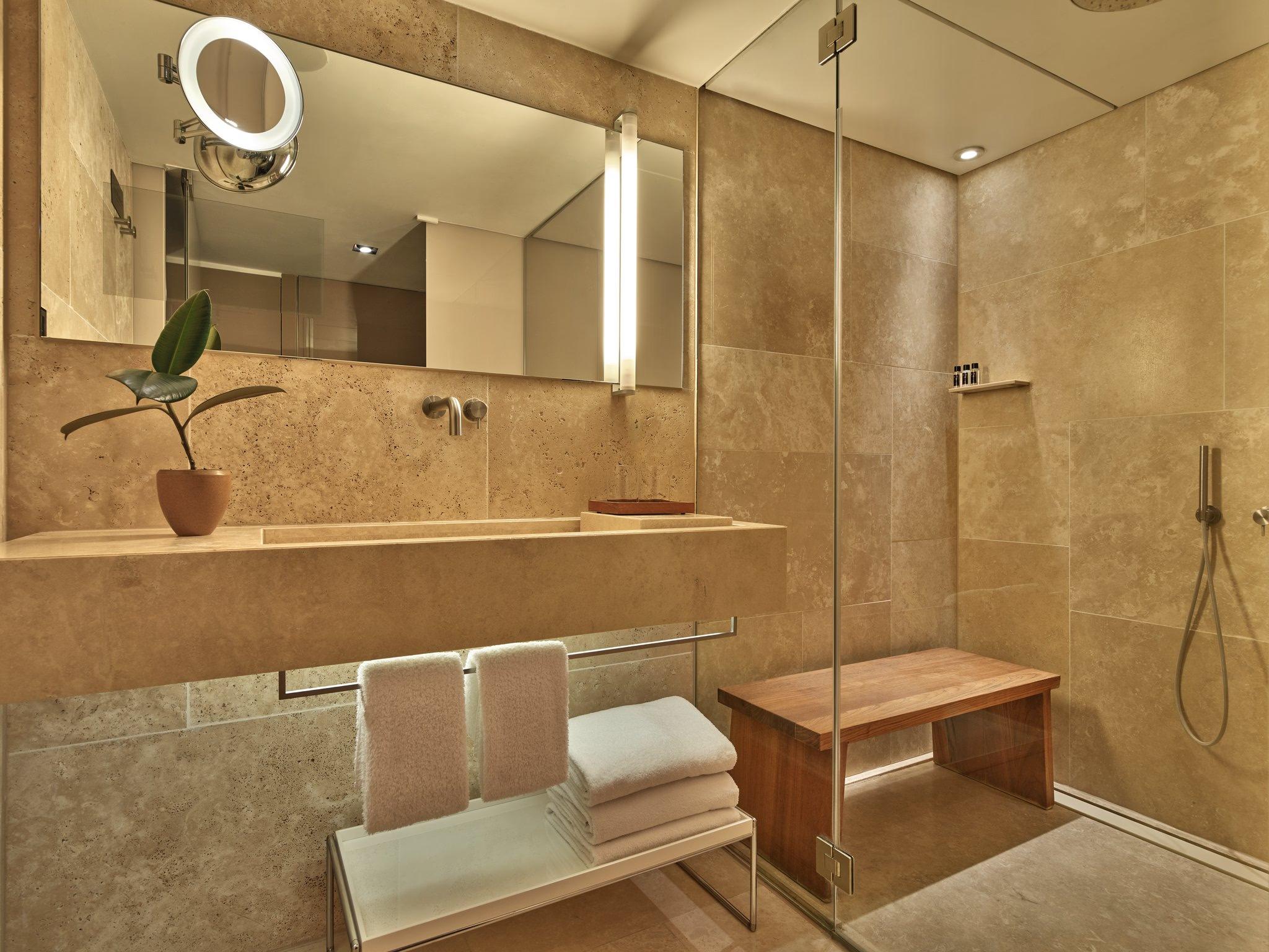 Mandarin Oriental Conservatorium, Amsterdam: spa-inspired bathroom with travertine walls, large mirror, and towel warming racks