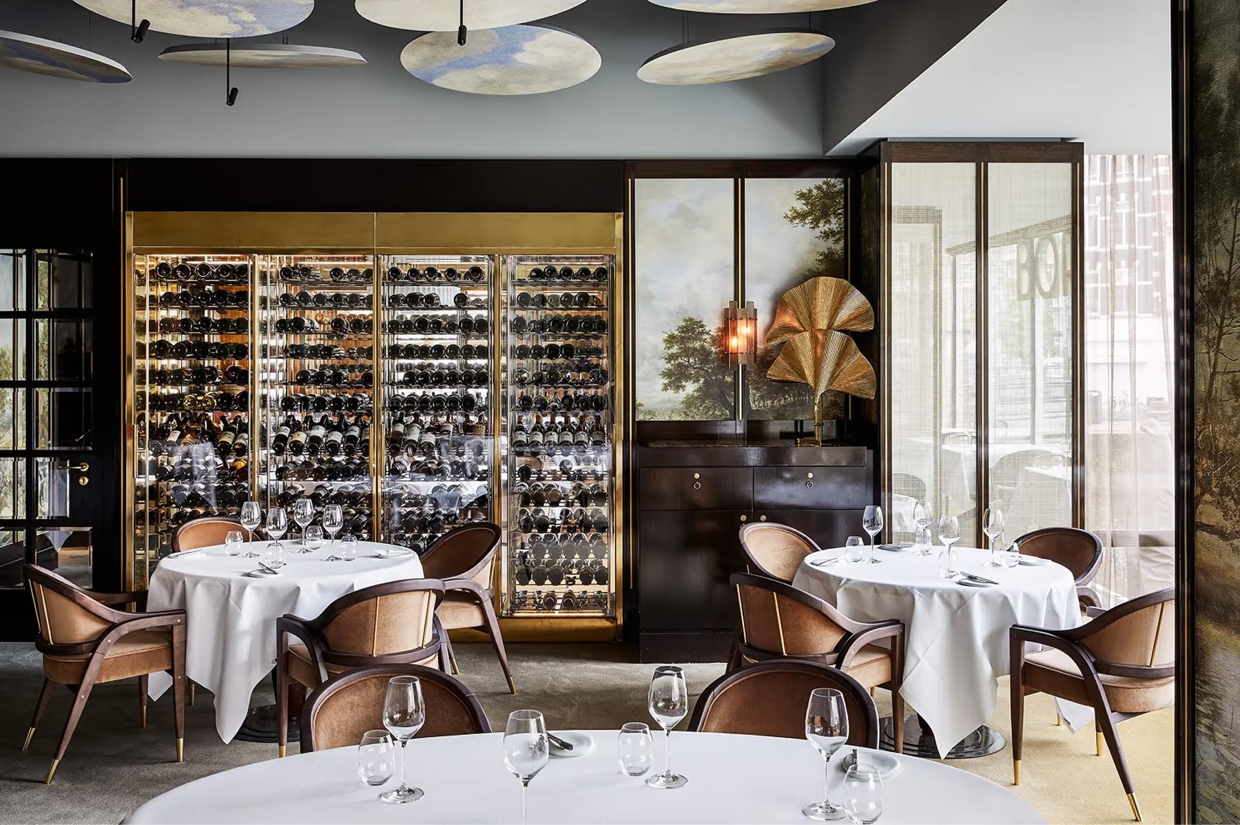 Contemporary dining space with glass wine cellar backdrop and minimalist table settings