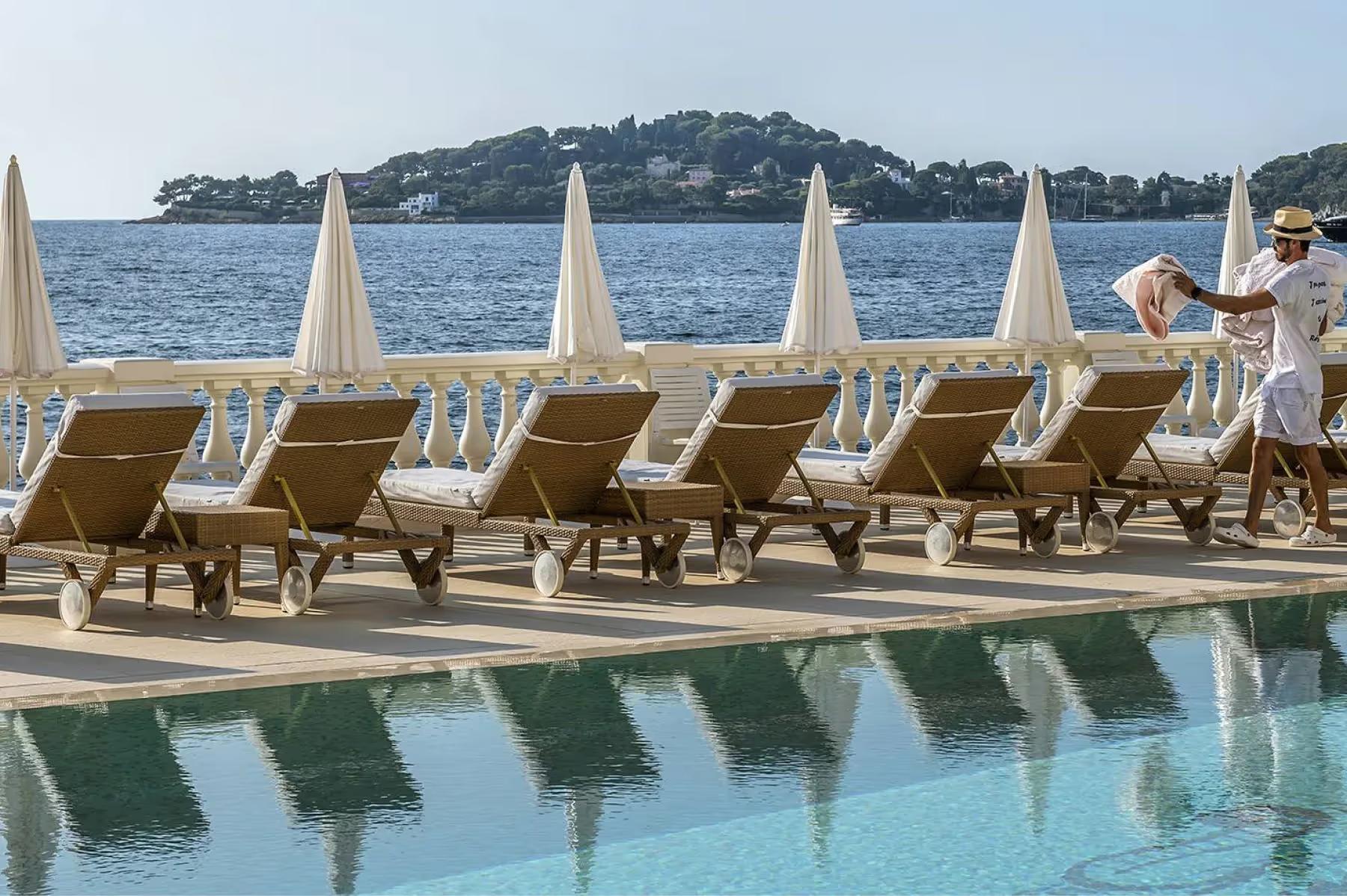La Réserve de Beaulieu: terraced pool with deck chairs and sailboats on the Mediterranean