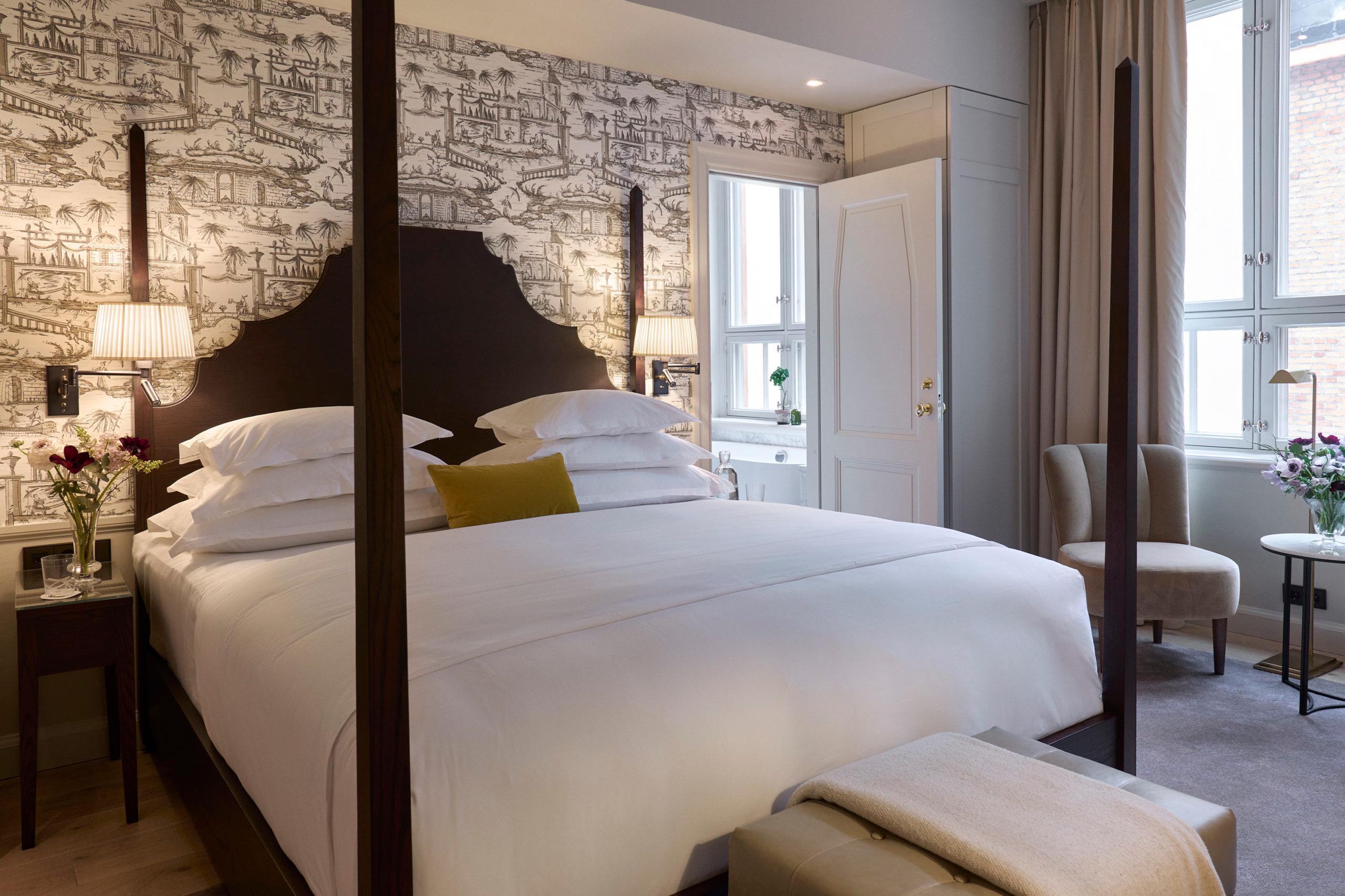 Guest room with brick accent wall, draped windows, and four-poster bed