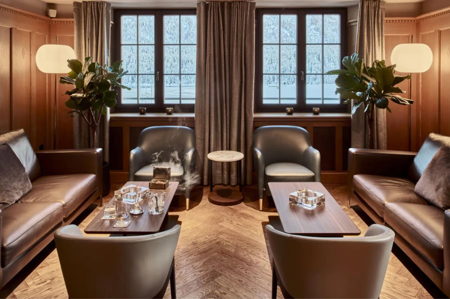 Grace La Margna St. Moritz: wood-paneled sitting room with leather seating, side tables, lamps, and window views