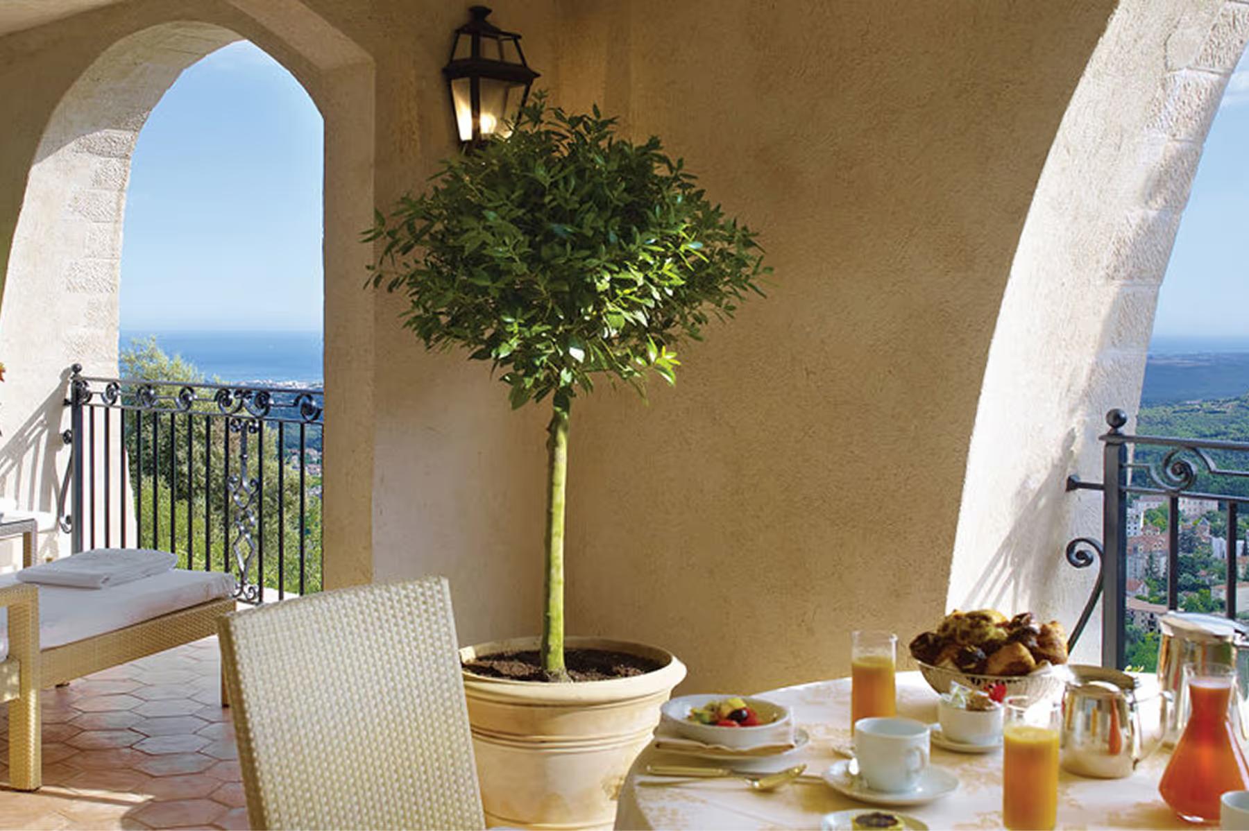 Arched balcony with sea views, lounge chair, and topiary planting