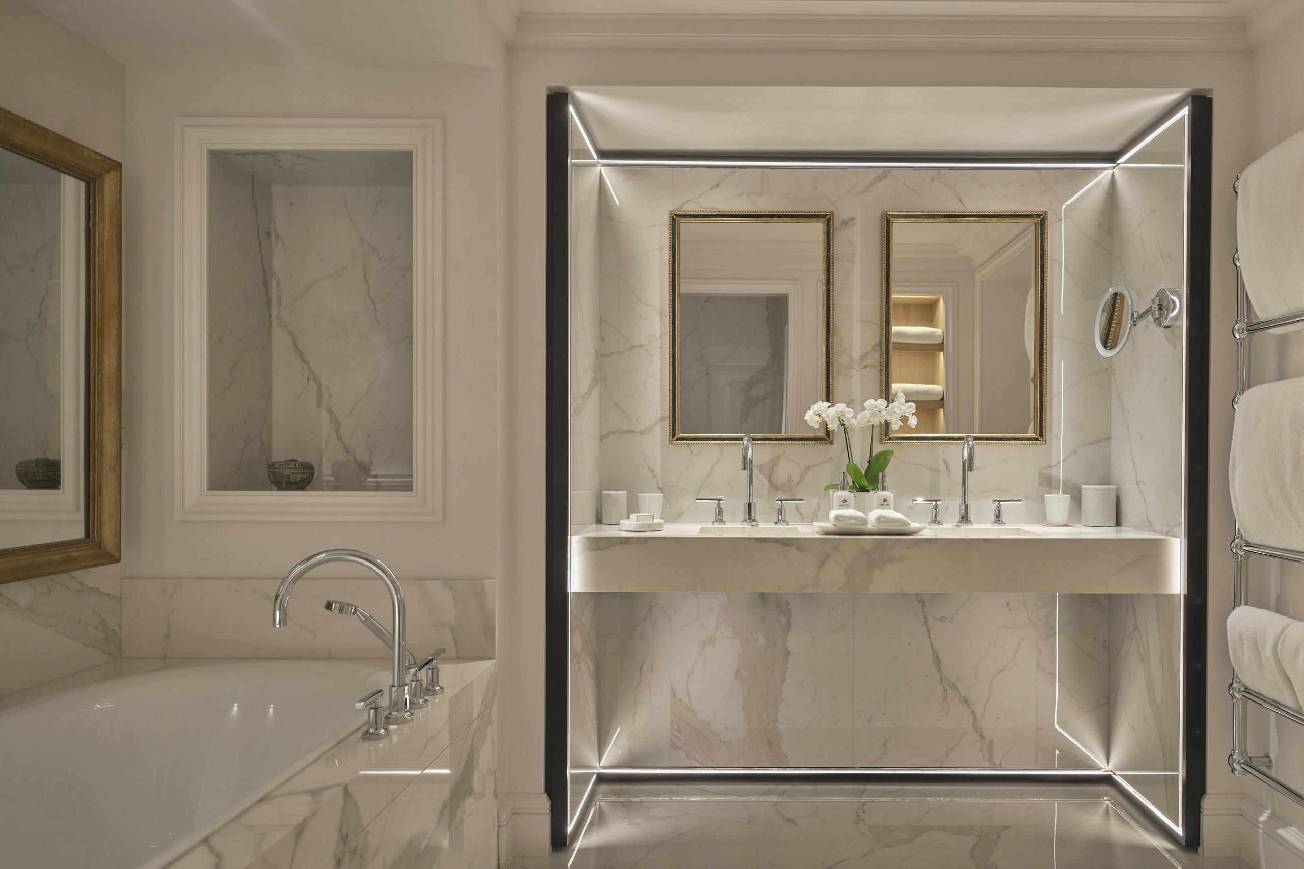 Marble bathroom with gold fixtures and a mirrored vanity cabinet