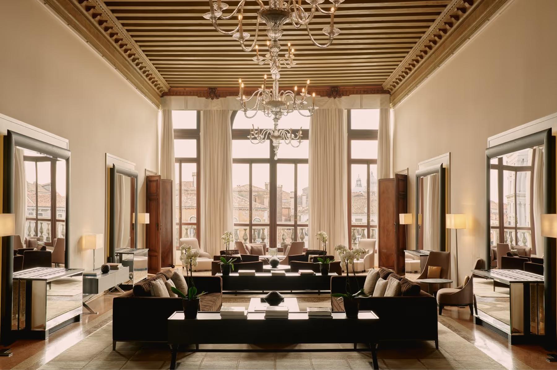 A luminous salon with a barrel-vaulted ceiling, tall arched windows, black upholstered seating, and marble flooring