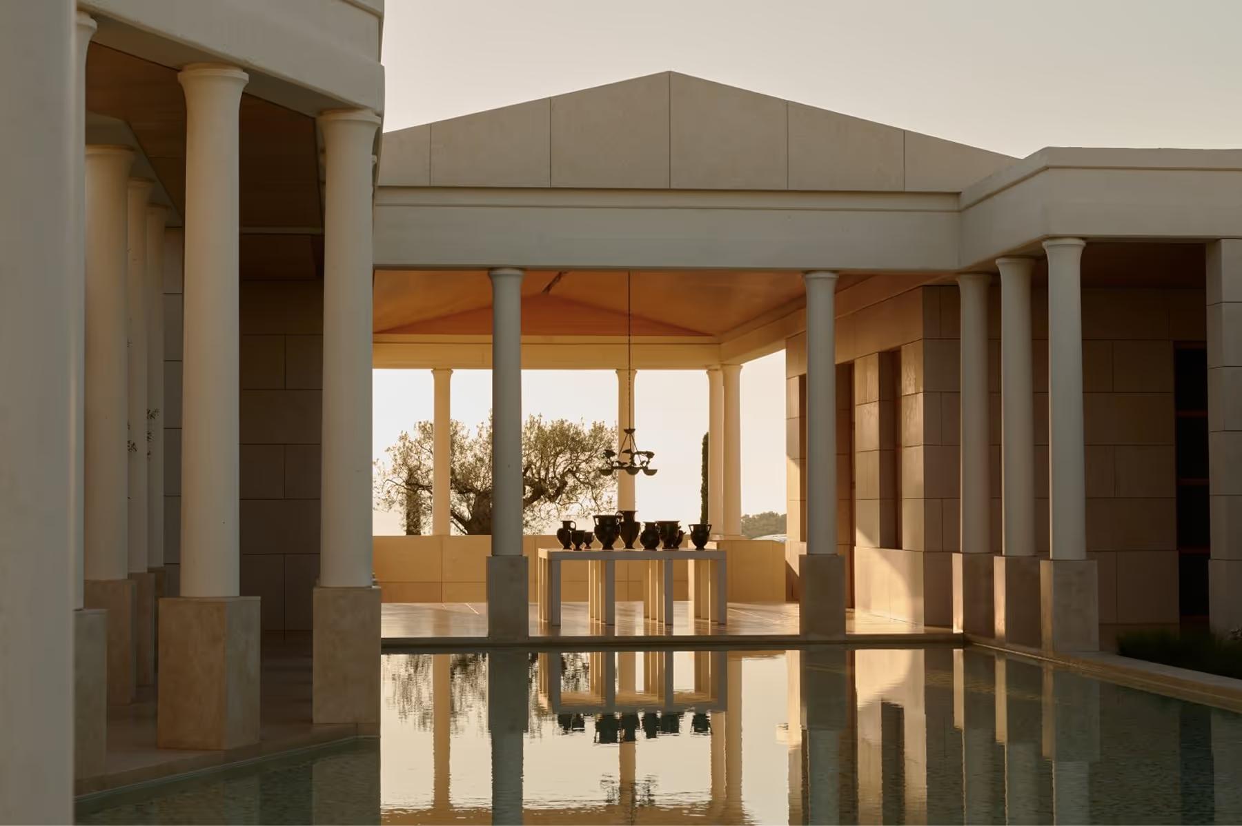 Minimalist pavilion with marble columns reflected in still water