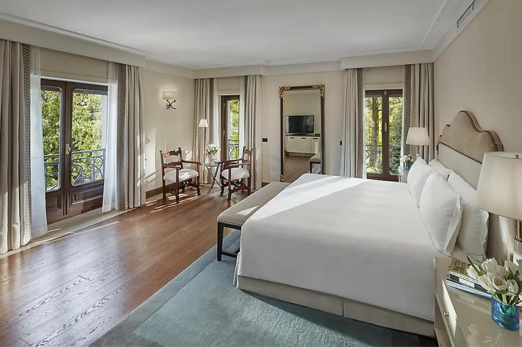 Spacious suite with multiple seating areas, wood accents, and floor-to-ceiling windows