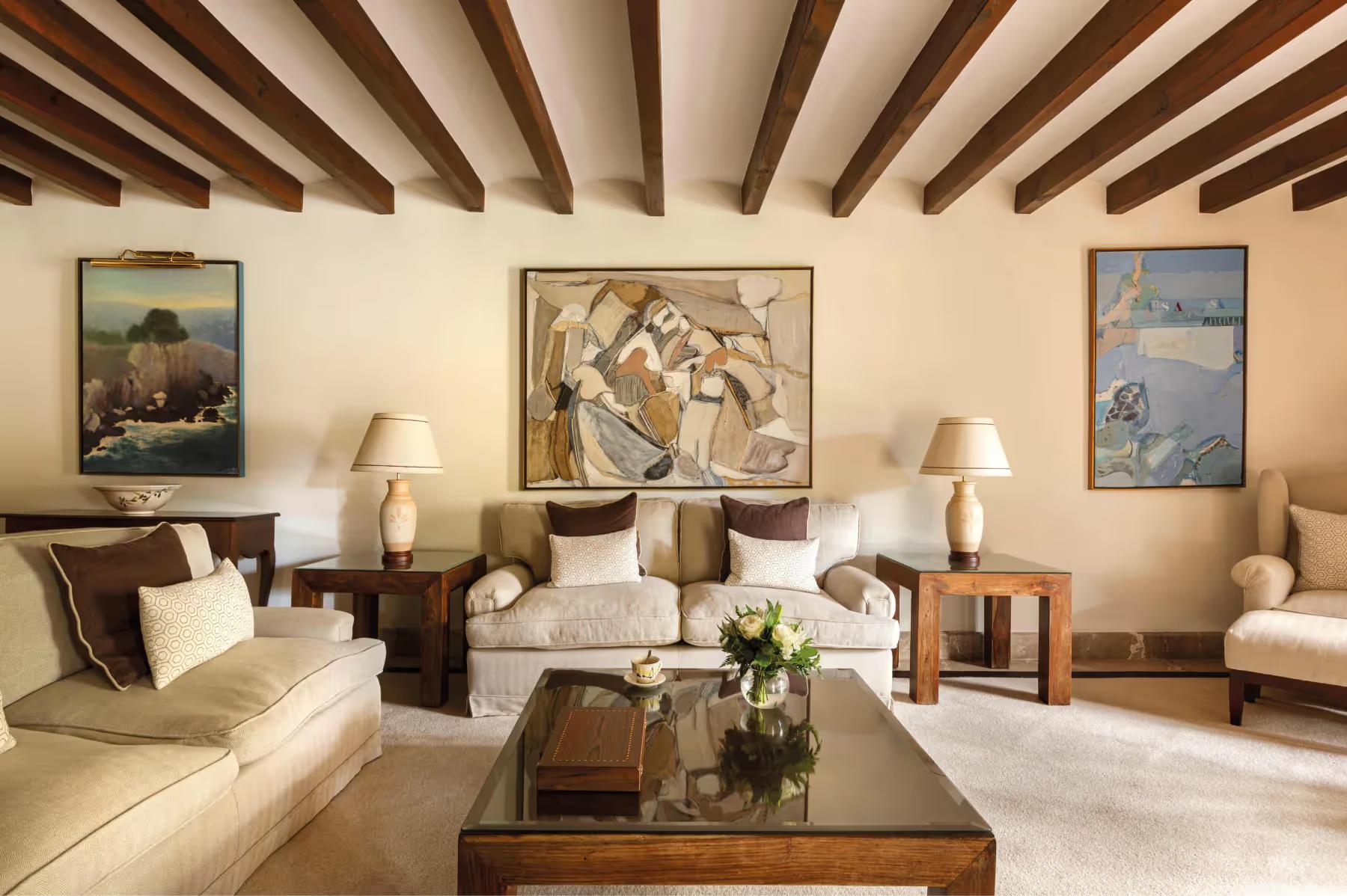 La Residencia: formal sitting area with beamed ceiling, cream-toned furnishings, framed artwork, and arched doorway