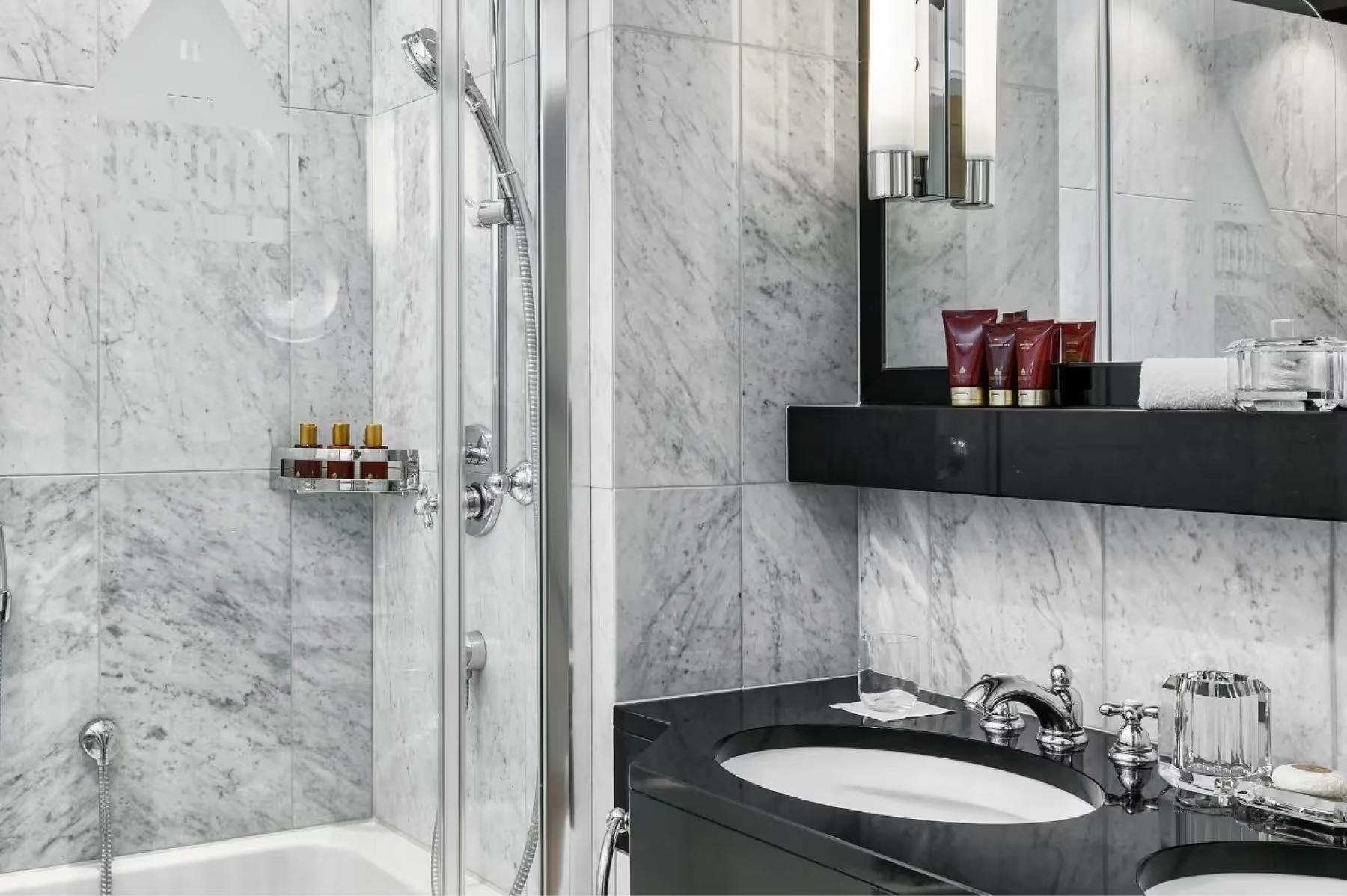 Bathroom with marble shower enclosure, black vanity, and brass accessories