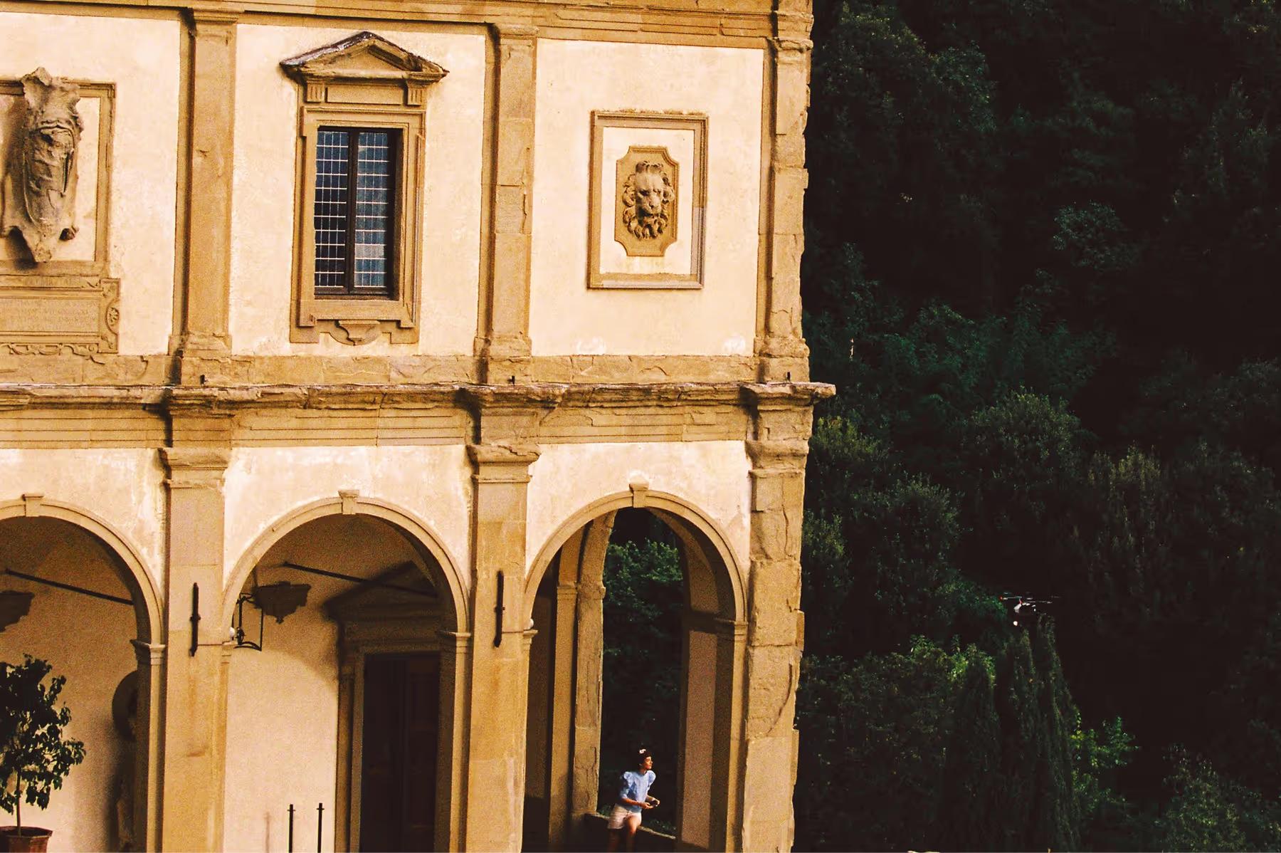 Villa San Michele: cream-colored Renaissance facade with arched columns, carved stone ornaments, and dense ivy covering the hillside