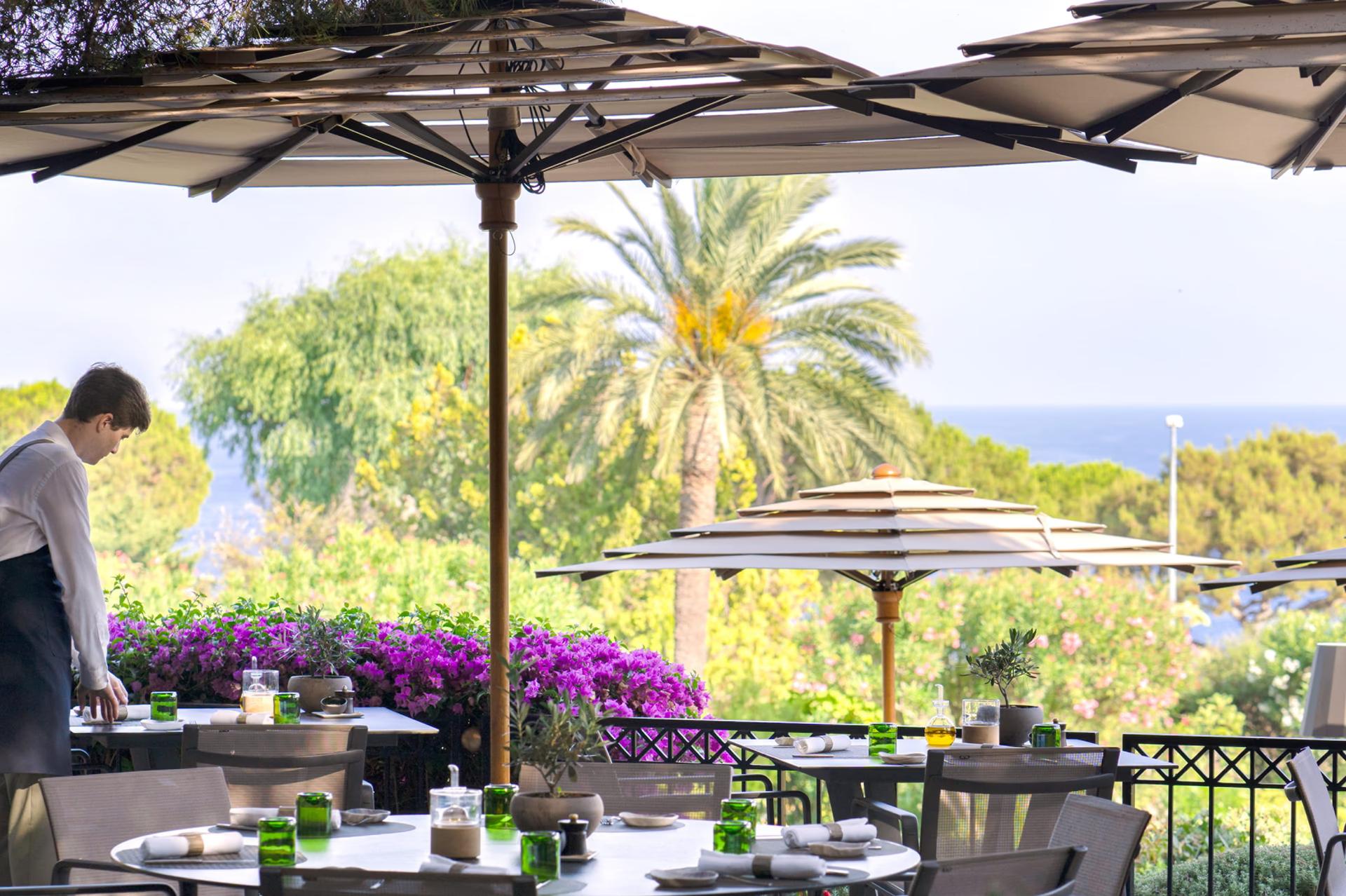 Grand-Hôtel du Cap-Ferrat: shaded deck area with umbrella and sea view above palm trees