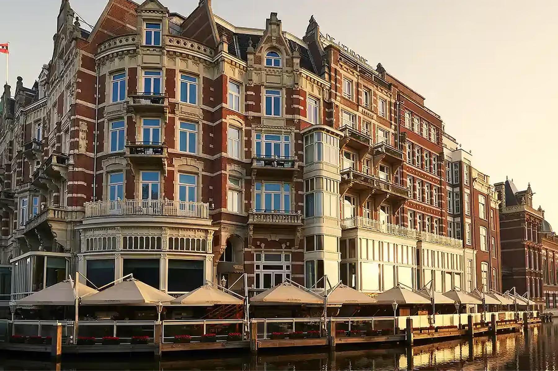 De L’Europe Amsterdam: red-brick historic building facade along the Amstel River with arched windows and decorative stonework